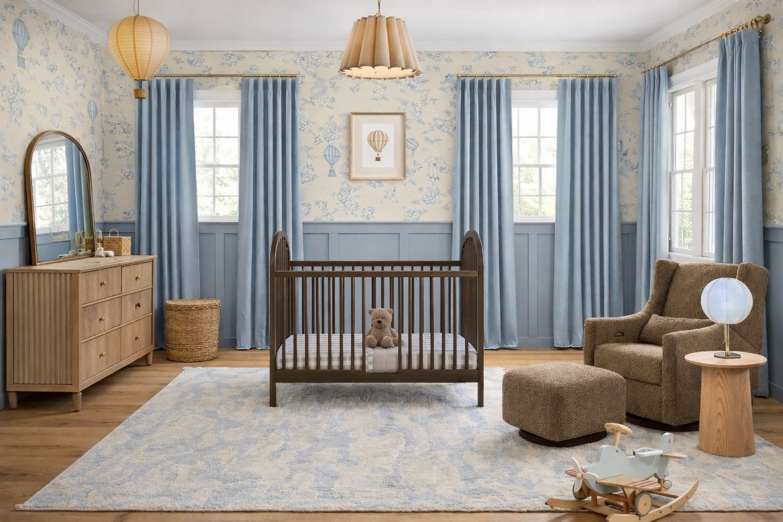 This aviation-inspired nursery is soft, timeless, and designed to grow with baby ✈️ The hot air balloon wallpaper layered across the entire room adds just the right amount of whimsy, while blue wainscoting grounds the space and keeps it calm. A centered crib anchors the layout, paired with a ribbed wood dresser, cozy glider, and natural textures for an organic feel. Neutral rugs, light wood accents, and soft blue drapery create a peaceful nursery that feels classic not themed. Save this for nursery inspiration, boy nursery ideas, and hot air balloon nursery decor.