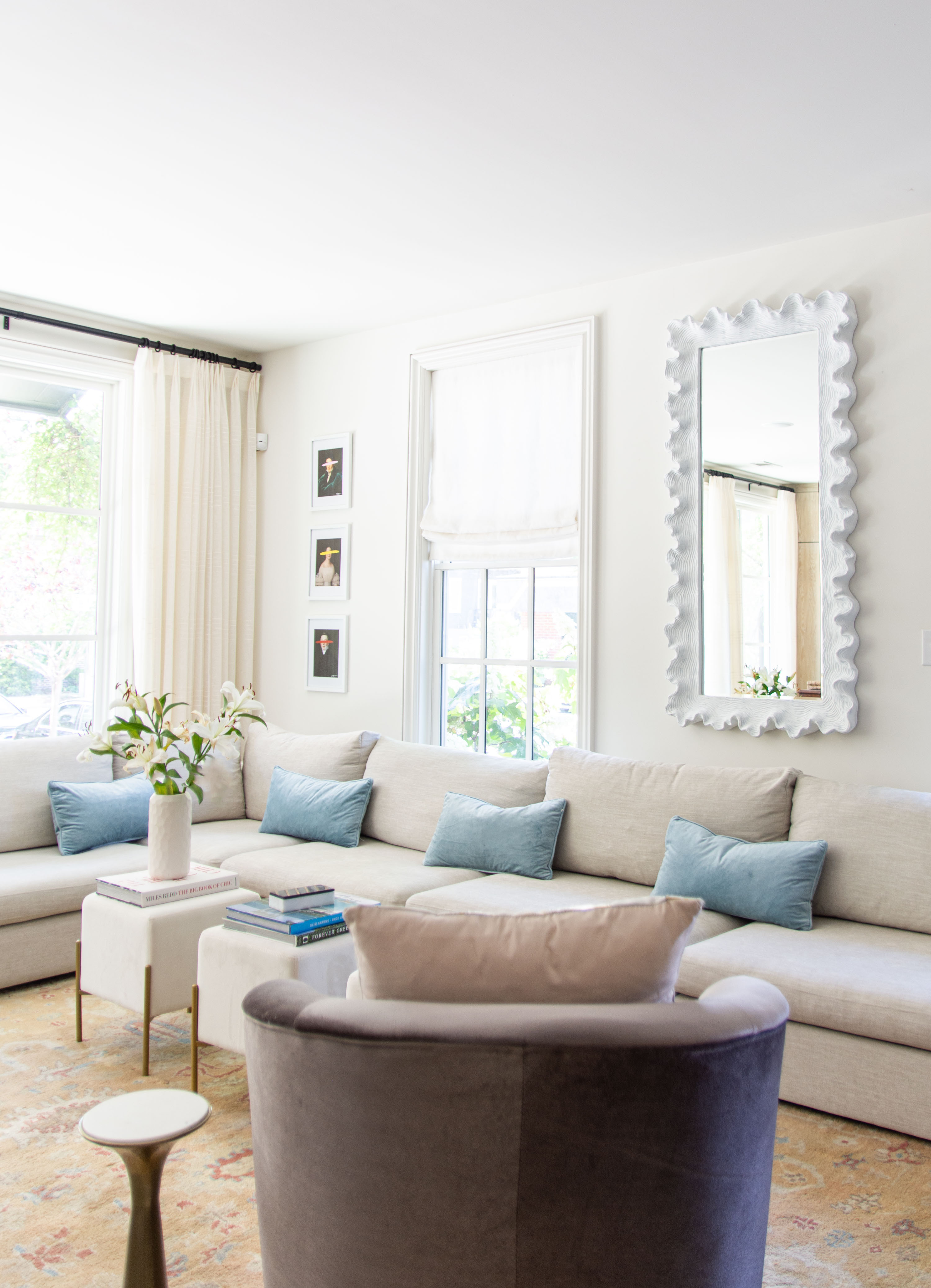 Bright and airy living room featuring a modern neutral sectional sofa styled with light blue accent pillows, a chic velvet swivel chair, and a sculptural white statement mirror. The space is layered with soft textures, elegant drapery, and a vintage-inspired rug for a cozy yet sophisticated feel. Perfect inspiration for neutral living room decor, transitional design, and timeless home styling. Shop the mirror, sectional sofa, accent pillows, and decor details to recreate this inviting look. 

 