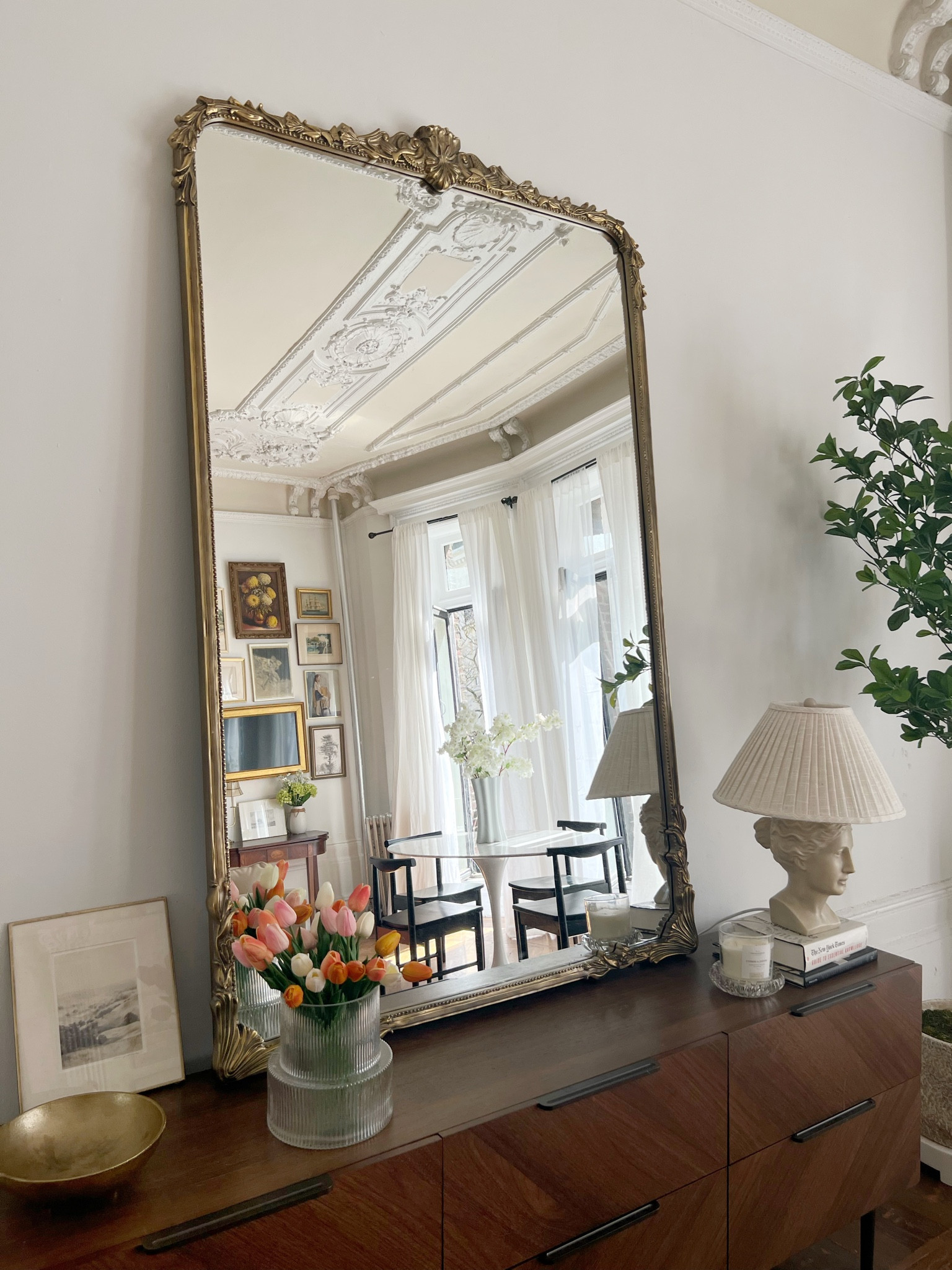 Horizontal, wood, dresser, gold floor, mirror, table, lamp, glass, fluted, vase, tulips, indoor tree, marble, oval, pedestal, dining table, black dining chairs, Spring branches linen curtains, sheer curtains

#LTKhome #LTKFind #LTKSeasonal