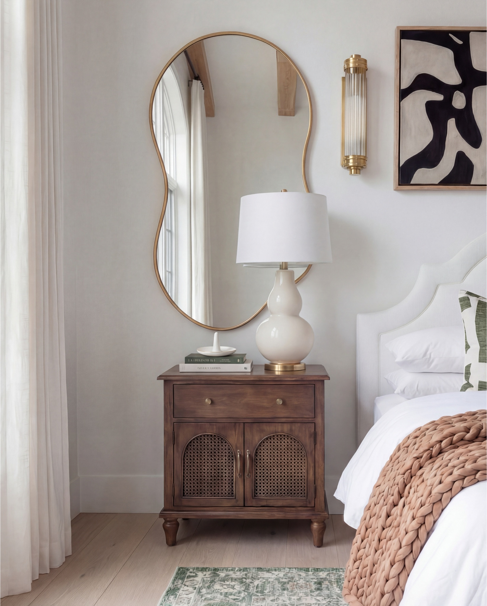 
This bedroom feels warm, tailored, and quietly elevated. The soft white upholstered bed keeps the space light and refined, while rich walnut wood tones and brass accents add depth and a subtle vintage influence. Green patterned textiles bring an earthy contrast against the neutral palette, and sculptural mirrors paired with layered lighting give the room a balanced, designer-finished look.

The styling feels relaxed but intentional—chunky knits, classic wood furniture, and simple ceramic decor create a cozy atmosphere without overwhelming the clean architectural lines and exposed wood beams.

Shop the Look:
• White upholstered arched headboard bed
• White cotton duvet cover + pillow shams
• Green vintage-style area rug (distressed pattern)
• Brown chunky knit throw blanket
• Dark wood nightstands with cane doors
• White ceramic table lamp (round base)
• Brass wall sconces with glass shades
• Organic shape gold wall mirrors
• Black and beige abstract framed wall art
• Green geometric throw pillows
• Upholstered brown bench (channel tufted)
• Dark wood dresser with brass pulls
• Round ivory accent chair
• Cream throw blanket (soft knit texture)
• Tall brass floor lamp with white shade
• Decorative book stack (neutral tones)
• Small wood decorative box
• Brass round tray
• White pedestal decorative bowl
• Marble candle holders with brass rings
• Taper candles (ivory)
• Large ceramic vase with dried stems

@Wayfair 

#LTKSaleAlert #LTKHome
