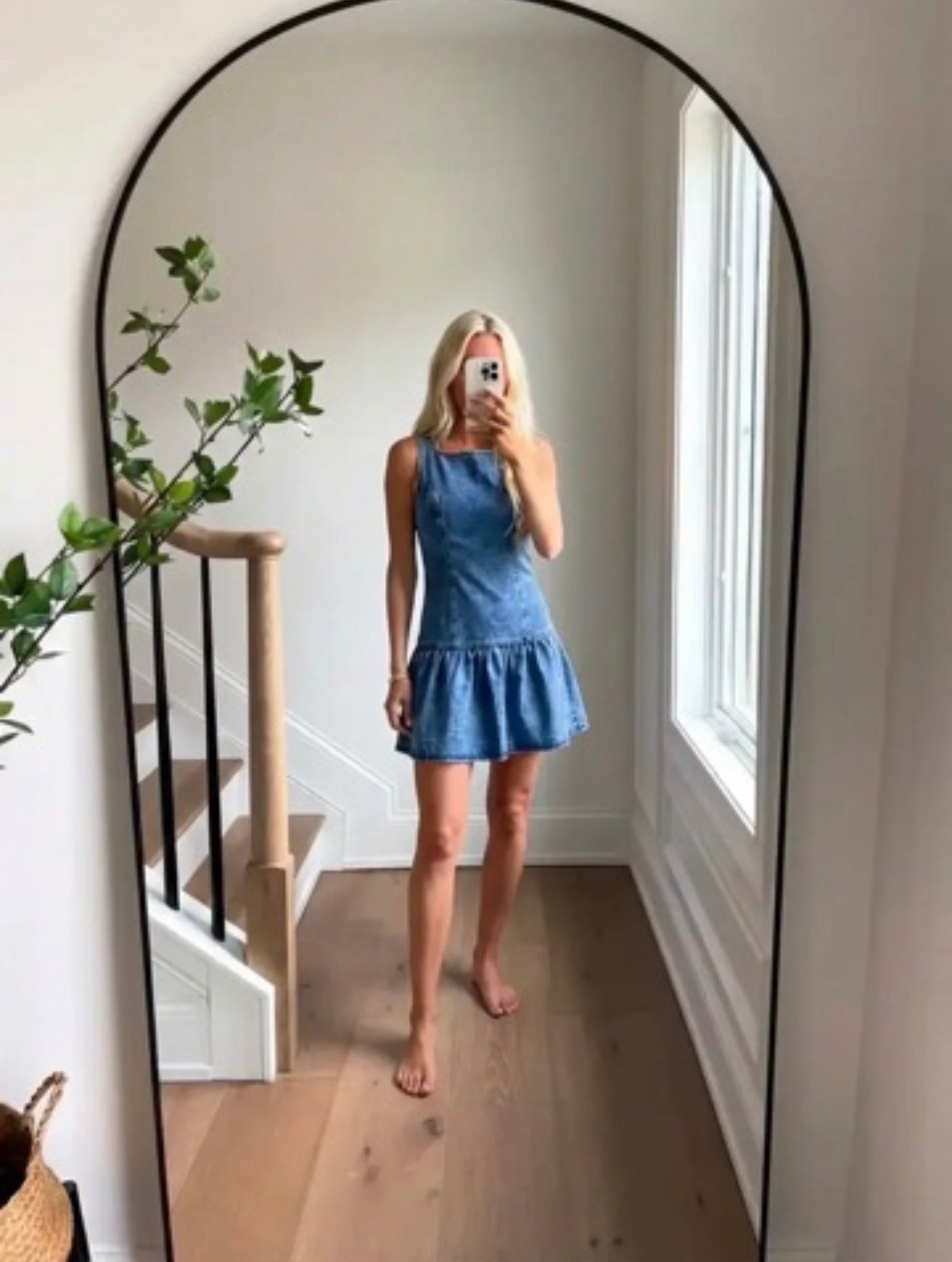 A minimalist lifestyle fashion scene featuring a woman taking a mirror selfie in a bright modern home. She is wearing a sleeveless blue chambray mini dress with a drop waist ruffle hem, standing barefoot on light natural oak floors. The space has a large arched black-framed mirror, soft natural light streaming through a tall window, neutral white walls, a staircase with light wood railing and black balusters, and a touch of greenery from a nearby plant. The aesthetic is airy, coastal-modern, effortless summer style, clean and editorial, soft natural lighting, relaxed luxury lifestyle photography.



Effortless mornings, natural light, and a dress that just makes you feel good. 💙

Hashtags

#EffortlessStyle
#ChambrayDress
#MinimalStyle
#SummerStyle
#MirrorSelfieStyle
#CoastalStyle
#CleanGirlAesthetic
#SimpleChic
#ModernHomeStyle
#CasualLuxury
#EverydayStyle
#NeutralHome
#OOTDInspo
#TimelessStyle
#MinimalFashion
#StyleInspoDaily
#EffortlessBeauty
#ChicAndSimple
#ClassicStyle
#StyleInfluencer

#LTKSpringSale #LTKdayinmylife #LTKgrwm
