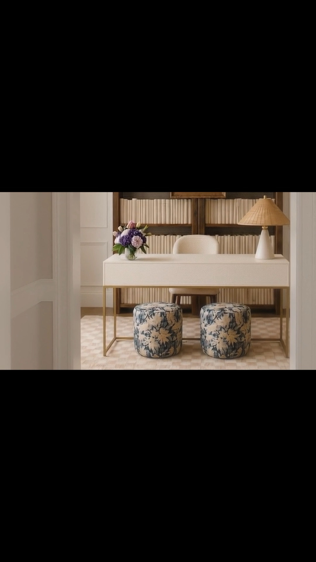 Modern, relaxed family home office — layered but easy.

Warm wood open shelving sets the foundation, while a creamy writing desk keeps the space soft and clean. The upholstered chair brings comfort without adding visual weight, making it feel like a place you can actually sit and stay.

I love how the checker rug adds quiet structure, and the floral ottomans bring in that collected, lived-in pattern — not too perfect, just right.

The statement-making chandelier anchors the entire space, adding sculptural interest without overwhelming the room.

And the art is everything here. Suspended in front of the shelving, it creates depth and becomes a focal point without closing off the space — curated, not fixed, almost floating.

The rattan table lamp softens it all — warm, natural, and relaxed, tying every layer together.

Calm, balanced, and livable — exactly how a home office should feel.

#HomeOffice #ModernClassic #WritingDesk #OpenShelving #CheckerRug #FloralOttoman #UpholsteredChair #RattanLamp #StatementLighting #WallArt #InteriorStyling #RelaxedLiving

#LTKSaleAlert #LTKMothersDay #LTKHome