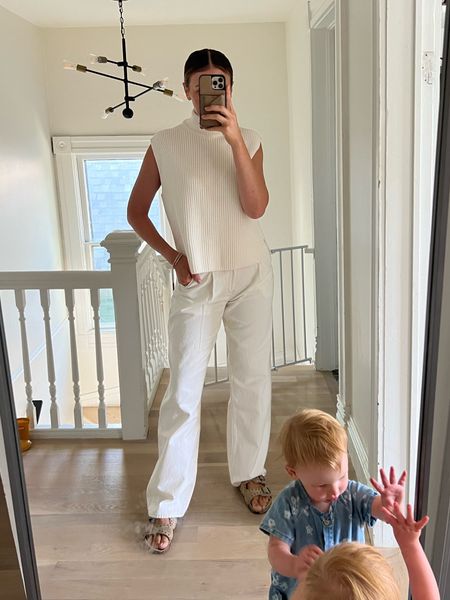 White loose jeans and sleeveless turtleneck sweater 