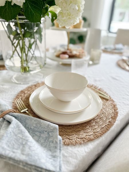Simple white blue and natural tone tablescape. White ceramic dish set with gold trim, woven round placemats, gold flatware, blue floral napkins, white table throw. Summer table setting, classic tablescape 

#LTKstyletip #LTKhome #LTKSeasonal
