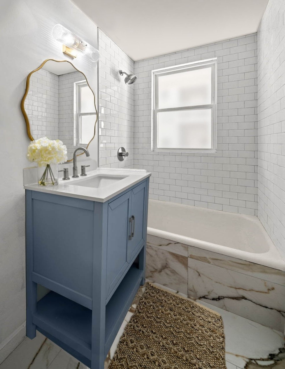 #AD we're thrilled to reveal the finished renovation of the second bathroom design #dwelloctoberstudio created as a design challenge featuring brand new @Lowe's products. when designing this bathroom, we were inspired by the gorgeous cornflower blue vanity and used this as the focal point of the room. we love its clean lines and classic coastal feel. we paired the vanity with a more organically-shaped wavy gold mirror and a fluted glass and gold sconce. modern brushed nickel plumbing fixtures and bathroom accessories add contrast to the gold finishes, while tying in with the vanity cabinet hardware. both the gold and nickel tones are reflected in the porcelain floor tile with its bold marble-inspired veining. simple white subway tile provides a clean, classic look for the shower walls. a woven jute accent rug with a chevron pattern and a pretty hydrangea floral arrangement add a bit of texture and warmth to the space. #LowesPartner #dwelloctober

#LTKHome
