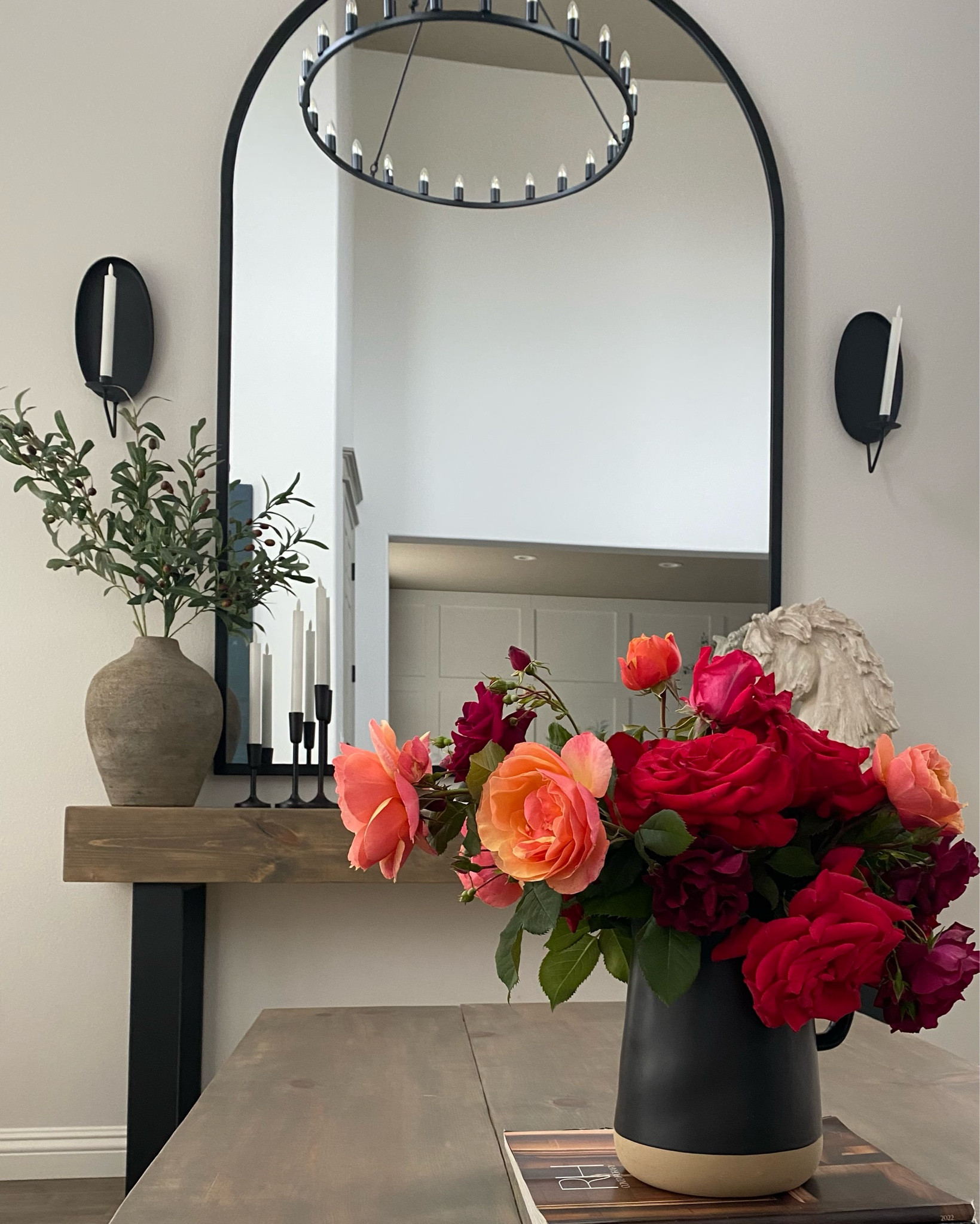 Get the look. Transitional living room. Neutral home decor. Wagon wheel chandelier. Arched floor mirror. Huge arch mirror. Black vase. Black candlesticks. Black candle holder. Candle sconce. Horse bust. 