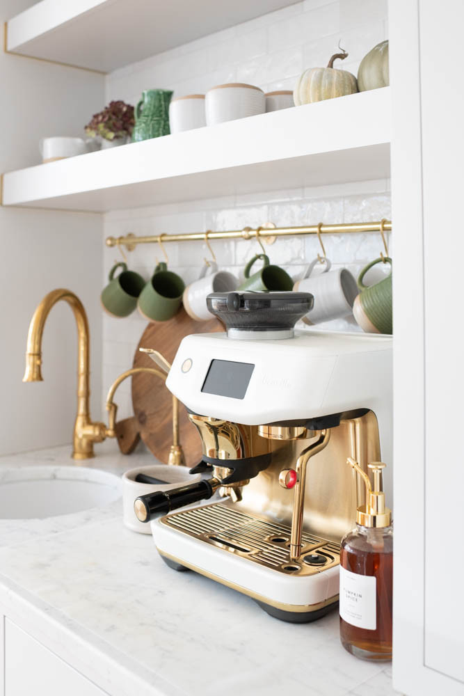 This autumn, I made a few cozy swaps to refresh the space. Mack surprised me with the cream-and-gold espresso machine for my birthday (I still can’t stop admiring it!), and over the weekend he hung the mug rail that looks like it’s always belonged there. I mixed in some green mugs with my classic Farmhouse Pottery ones to bring in a fresh color for the season. Now, every morning feels a little more beautiful, with a reminder to slow down and savor small joys.
A couple of other tips from the coffee station that you can save if you're renovating or redecorating:
🍁 A clear silicone mat protects our marble countertops from drips and spills, but it's nearly invisible.
🍁 When we renovated our kitchen, I had a hot water faucet installed for quick Americanos and tea. A plug-in kettle works great as well!
🍁 The picture light provides a soft glow so that I can avoid the "big lights" first thing in the morning. There are cordless options available now as well! 

 #LTKSeasonal #LTKHome