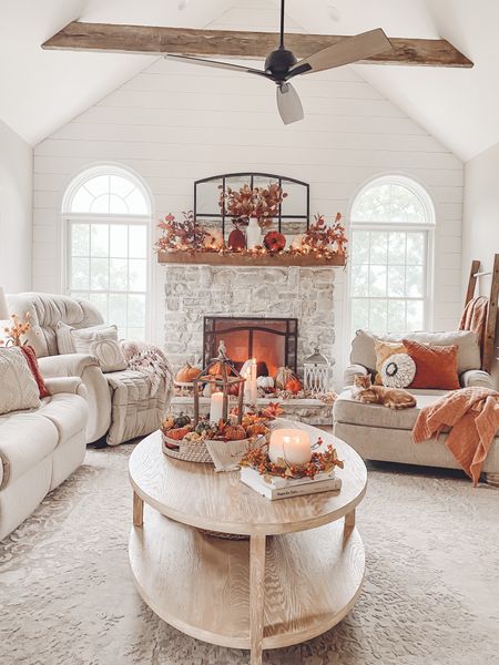 Living room, autumn decor, oval coffee table, ceiling fan, fireplace arched metal mirror, fall stems and florals, pumpkins, magnolia leaves, throws, candles, decorative tray, fall throw pillows, mantle decor, coffee table books.

#LTKHalloween #LTKhome #LTKHoliday