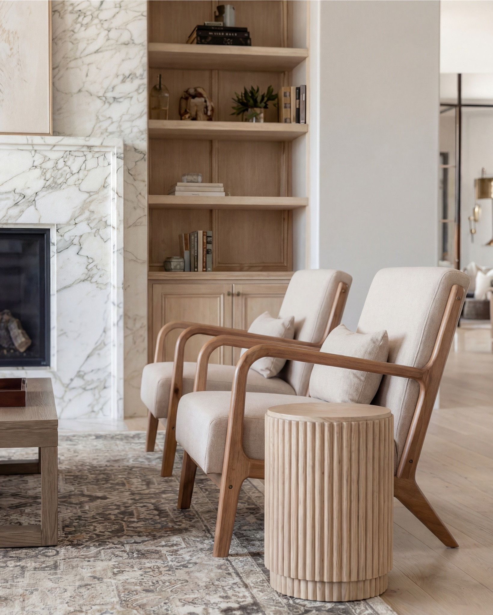 This living room is giving warm modern luxury in the softest, most elevated way. The marble-wrapped fireplace instantly becomes the star—clean, dramatic, and so timeless—and the light oak built-ins on both sides add that natural texture every cozy space needs.

The exposed beams tie the whole palette together, bringing warmth up to the ceiling and making the room feel intentionally architectural. And the furniture… neutral, sculptural, and perfectly layered. The cream sofa with tonal patterned pillows keeps everything calm, while the wood-frame accent chairs bring in that airy, organic feel.

The coffee table styling is chef’s kiss—a vintage-inspired rug, textured ceramics, stacked books, and a simple tray moment that adds just the right amount of depth.

Shop the Look:
• Cream upholstered sofa
• Oak wood accent chairs (curved arms)
• Marble-look fireplace décor
• Solid wood coffee table
• Neutral vintage-style area rug
• Ceramic vase + beads styling set
• Light oak built-ins (or styling pieces for shelves)
• Tan patterned throw pillows
• Soft woven throw blanket
• Wood Decor beads

#LTKsale #LTKhome #LTKstyletip