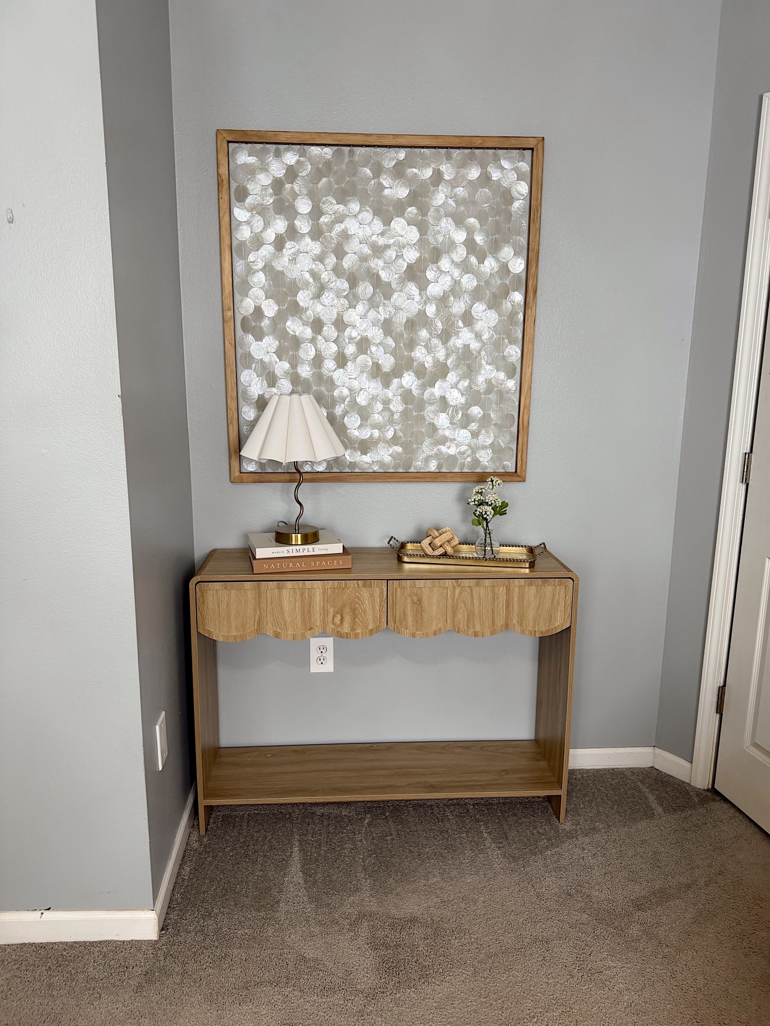 New filming space refresh 🤎 Went with a neutral mid-century style with coastal elements for my beach loving heart 🐚 
Mother of pearl Capiz shell wall art, light wood scalloped entry table, gold tray, lamp and aesthetic book storage 

#LTKSpringSale #LTKSeasonal #LTKHome