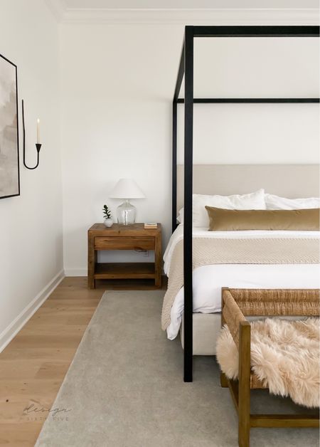 Neutral bedroom decor, black canopy bed, end of bed bench, nightstands, long lumbar pillow, table lamps, candle sconces, neutral rug 

#LTKhome