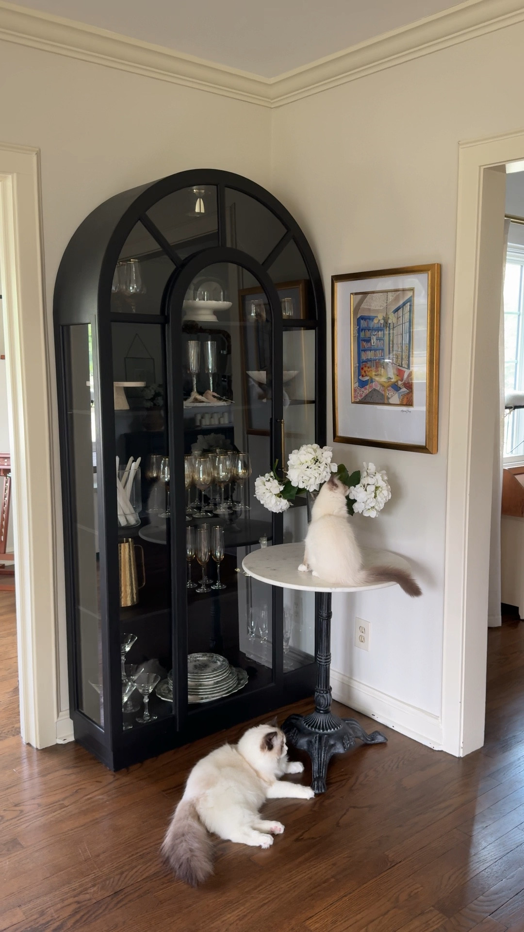 Beautiful black arched cabinet and bookshelves to elevate any space! Mine was a thrift flip but I love how this corner in our entertaining area came together with faux hydrangeas in a glass footed vase on this marble top bistro table!

#LTKHome #LTKSaleAlert #LTKFindsUnder100