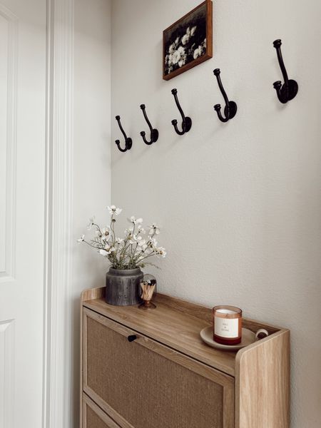 small entryway 🤍✨

that is budget friendly and functional! This is the entry we have by our garage and my husband’s home office. We used to have a console here where I stored our shoes but when I stumbled on this cabinet that concealed everything I knew it would be absolutely perfect here! I LOVE it!

details here:
+ shoe storage cabinet: very affordable and under $80 🤯
+ black planter: Walmart
+ faux florals: these are from Hobby Lobby but found near identical ones on amazon
+ candle I love
+ little candle tray that is an older Target find
+ artwork from Amazon
+ washable runner
+ hooks: Amazon find (still deciding if I want to keep these here. I can still hang shorter sweaters and jackets but because this cabinet is taller than my last, I might remove them. We’ll see 😌)

everything here is linked in my bio! What do you think of it? 👀



#LTKhome #LTKSeasonal #LTKfindsunder50