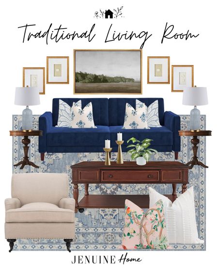 Art print. Intaglio in gold frame. Blue and white floral throw pillow. Dark wood coffee table. Gold candlesticks. Pink floral throw pillow. Neutral arm chair. Blue traditional rug. Blue lamp. Wood side table. Navy couch. Faux plant  