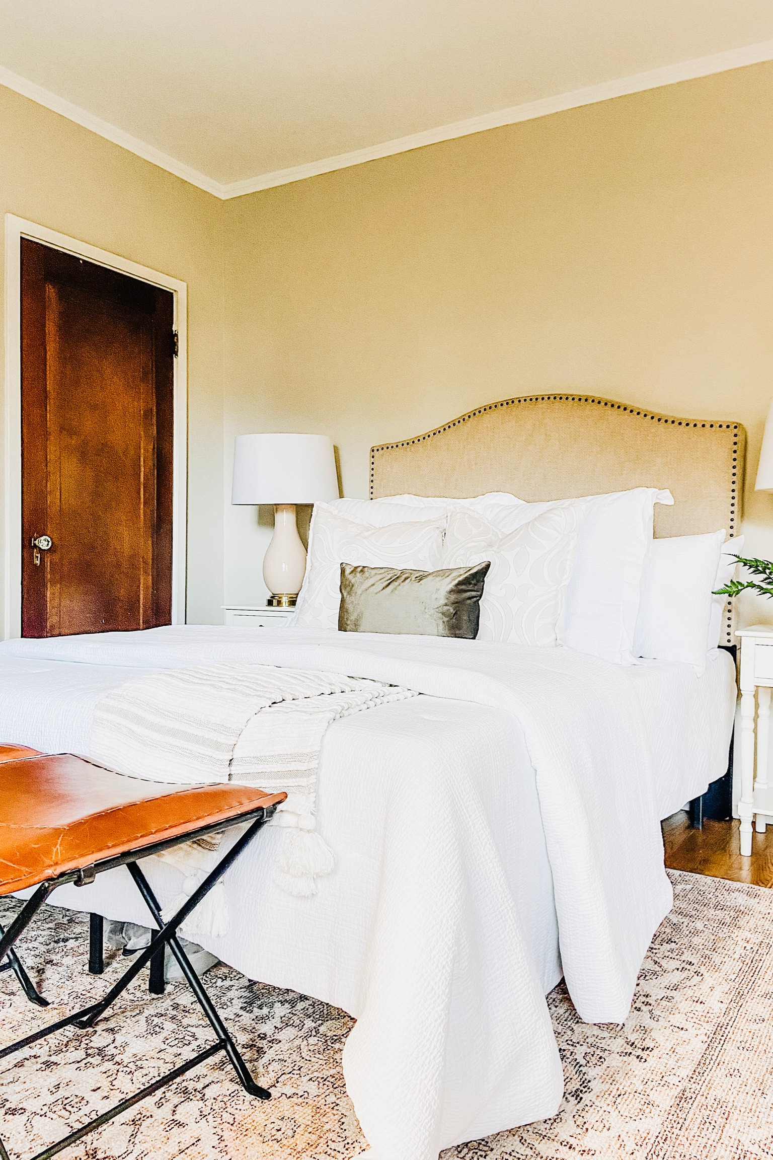 Freshen up your bedding and accent pieces with muted colors before the holidays!
.
.
.
White Bedding 
Upholstered Headboard with Bronze Nailheads 
Green Velvet Pillow
Rose and Gold Lamp
Neutral Throw Blanket
Leather Bench
Bedroom Decor