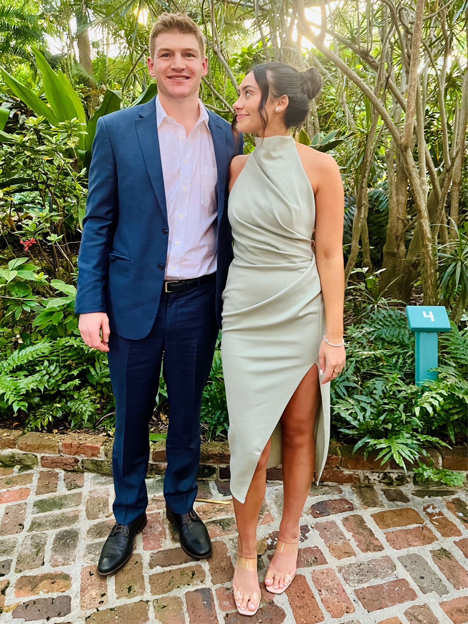 Cocktail wedding attire couple. navy blue suit, Sage green cocktail dress with high neck and slit. Updo with cocktail dress. Spring, summer or fall wedding guest dress 