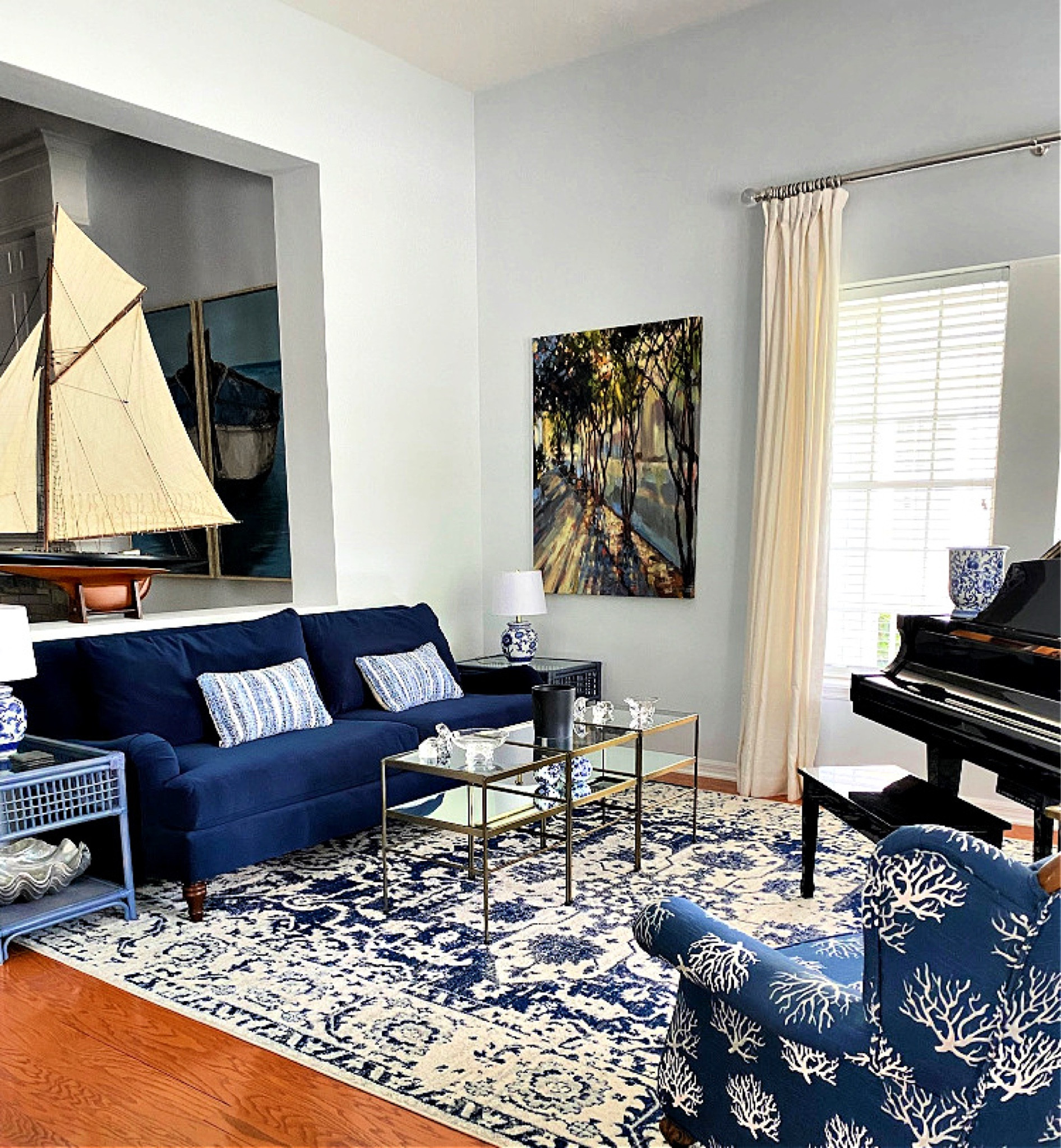 A serene blue and white living room that exudes timeless elegance and a touch of coastal charm. Crisp white walls and plush seating in deep blue tones create a calming foundation, while a patterned area rug brings in subtle visual interest. A driftwood coffee table serves as a centerpiece, surrounded by natural textures like woven baskets and sisal accents. Coastal nods include a coral patterned antique chair and an oversized sailboat model.  Soft, sheer curtains let in plenty of natural light, enhancing the airy, tranquil atmosphere.  This luxurious rug is only $247.99 for 10’x 14’!! 

#LTKHome