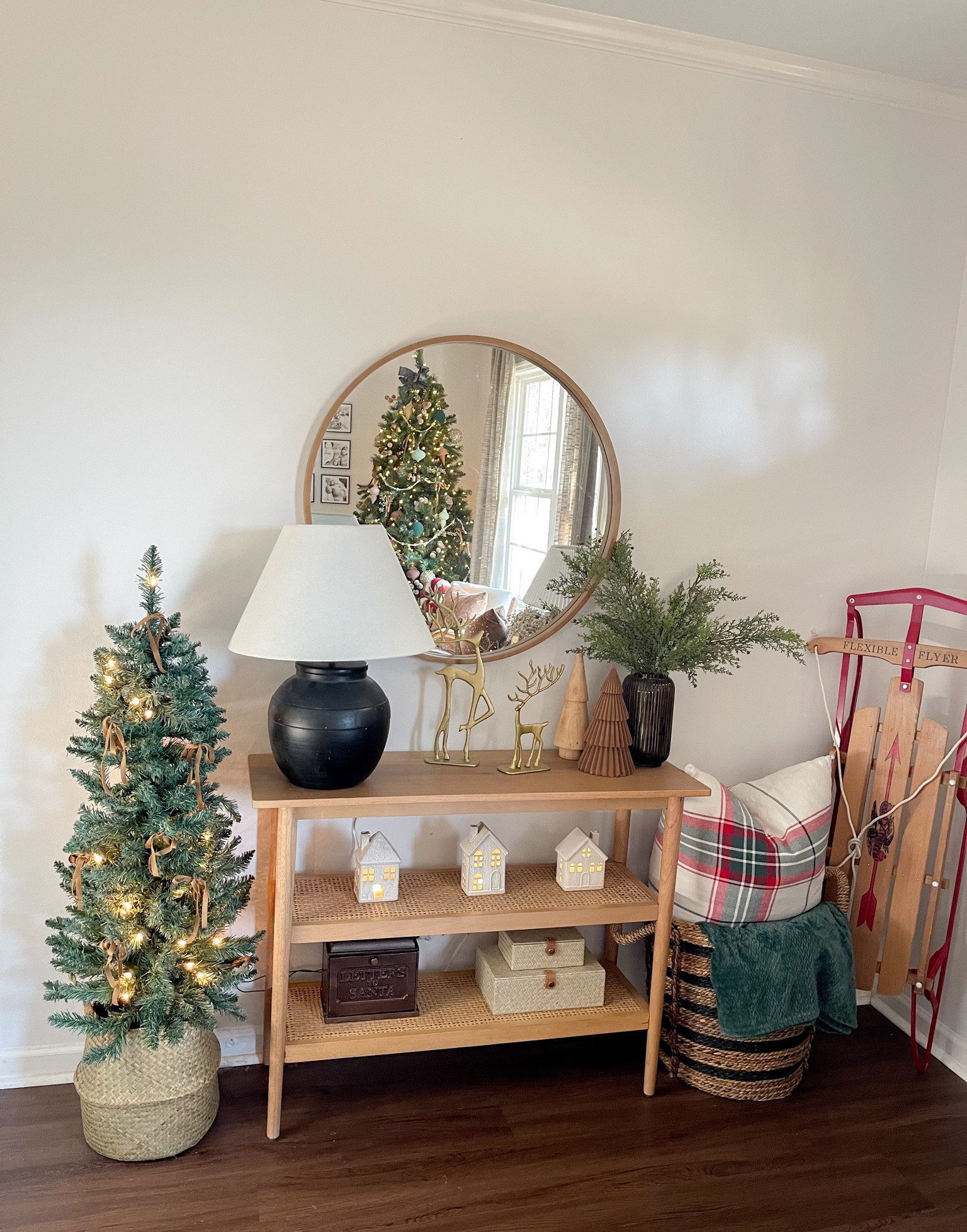 Entryway Christmas styling. Round mirror. Console table. Christmas tree. Christmas pillow. Ceramic houses. Letters to Santa. Woven baskets. Black lamp. 

#LTKSeasonal #LTKhome #LTKHoliday