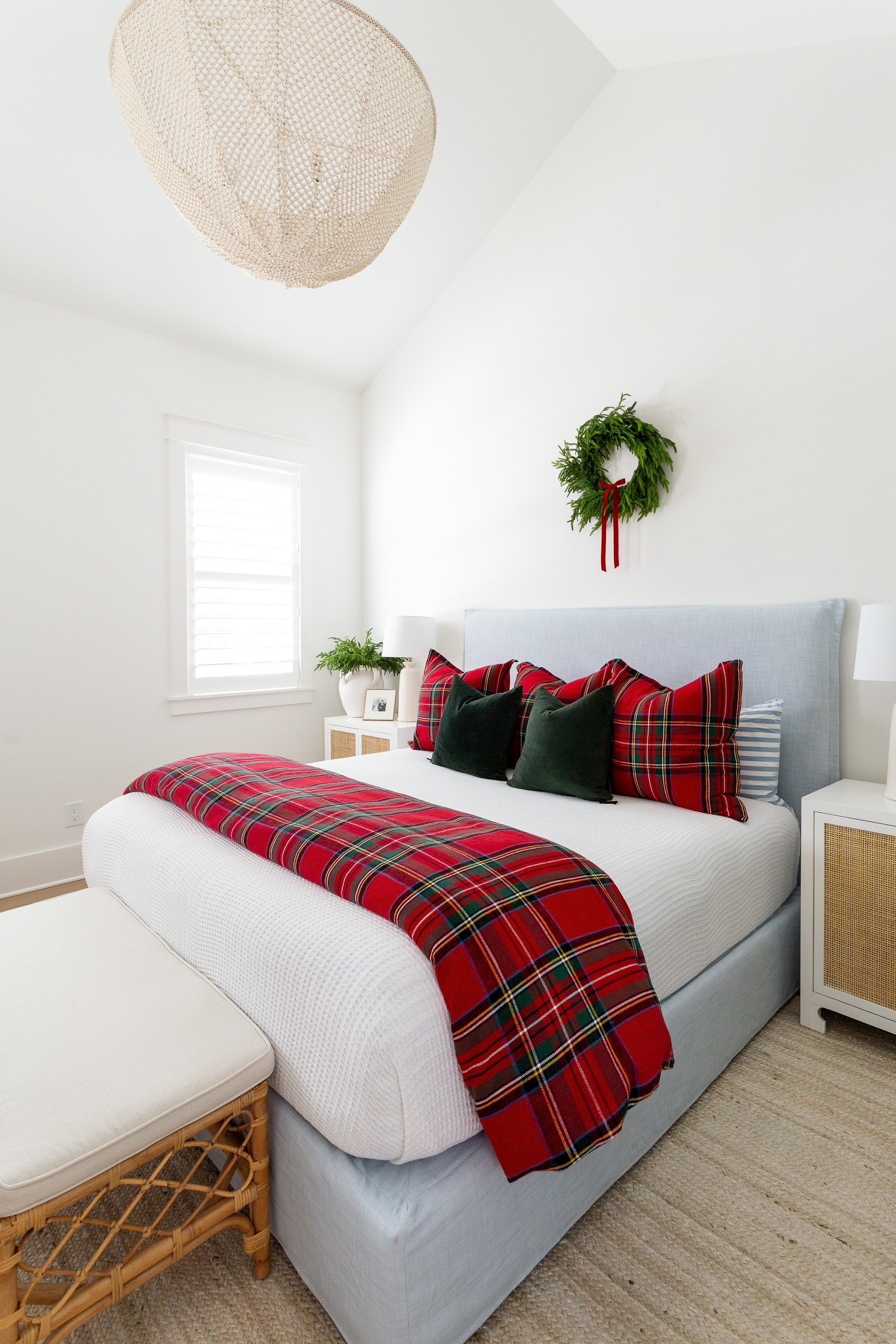 Christmas bedroom with vaulted ceilings, a light blue linen bed, white and red plaid bedding, dark green velvet pillows, a wreath with red velvet bow above the bed, bead chandelier, rattan nightstands, a rattan bench, and white jute rug. See our full Christmas home tour here: https://lifeonvirginiastreet.com/2024-christmas-home-tour/. #ltkholiday #ltkhome #ltksalealert #ltkfindsunder50 #ltkfindsunder100 #ltkseasonal #ltkstyletip 

 

#LTKHoliday #LTKSaleAlert #LTKHome