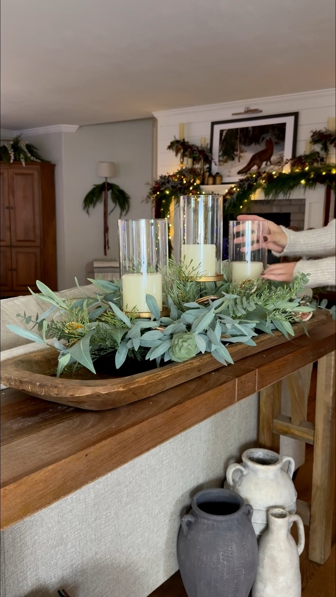 There’s something magical about a long dough bowl tray filled with a premade eucalyptus citrus centerpiece—the textures, the citrusy greenery, the effortless charm. Paired with hurricane candleholders and soft flameless candles, it becomes an inviting glow that feels both cozy and elevated. This easy centerpiece idea works beautifully on dining tables, kitchen islands, buffets, or coffee tables, giving your home that natural, collected look with zero fuss. A perfect blend of simple table décor, warm lighting, and seasonal greenery that feels like a quiet moment of beauty.
