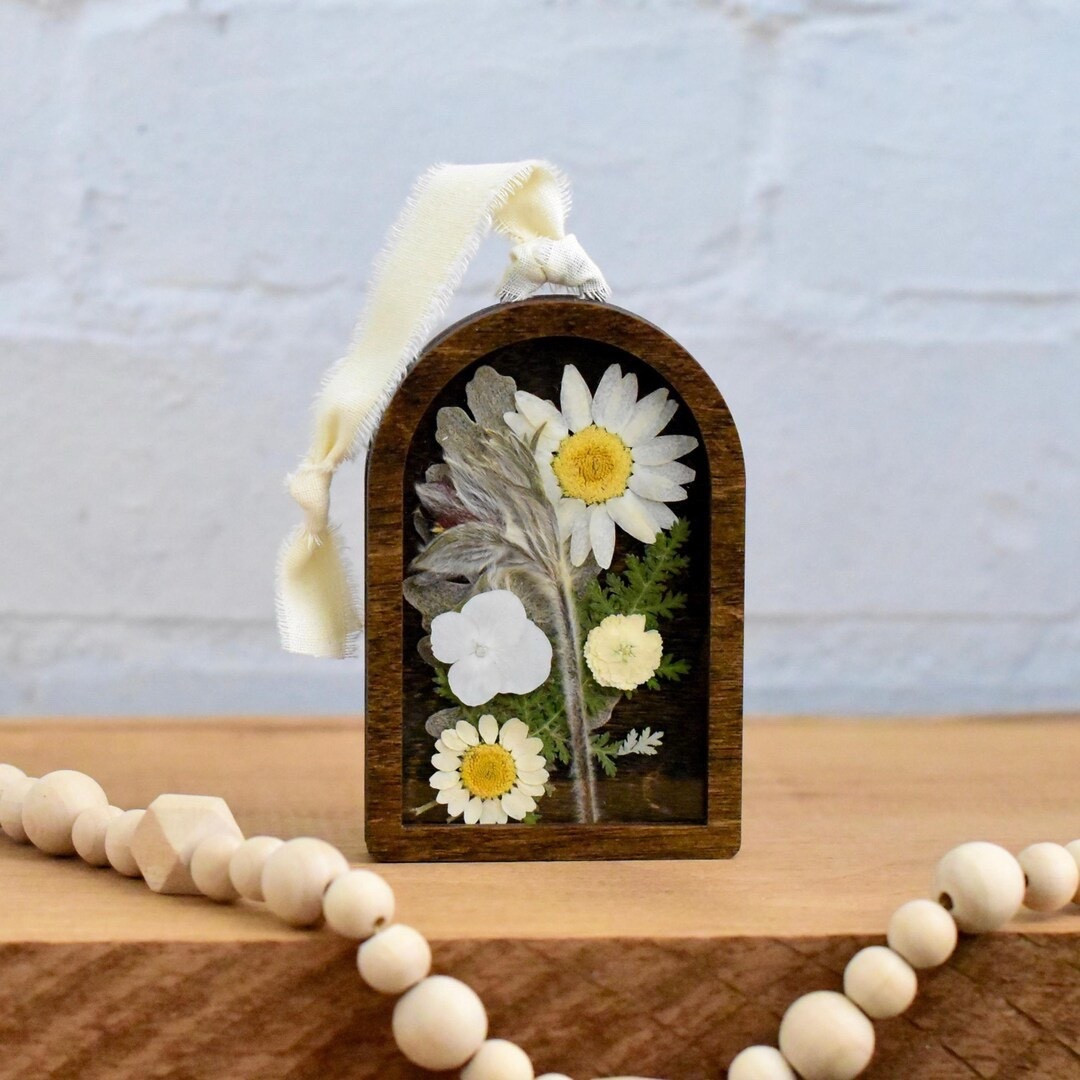 Add a touch of woodland charm to your tree with this beautifully crafted pressed flower ornament. Made from laser-cut Baltic birch and sealed with a soft satin finish, each piece frames real dried blooms behind a clear acrylic window for a delicate, nature-inspired look. With multiple floral styles to choose from and a rustic cotton ribbon for easy hanging, it arrives tucked inside a cotton gift bag—perfect for holiday gifting or safekeeping year after year. #LTKHoliday #EtsyFinds #PressedFlowerOrnament #NatureInspiredDecor #BohoChristmas #GiftIdeas #FloralHolidayDecor

#LTKSeasonal #LTKHoliday #LTKGiftGuide