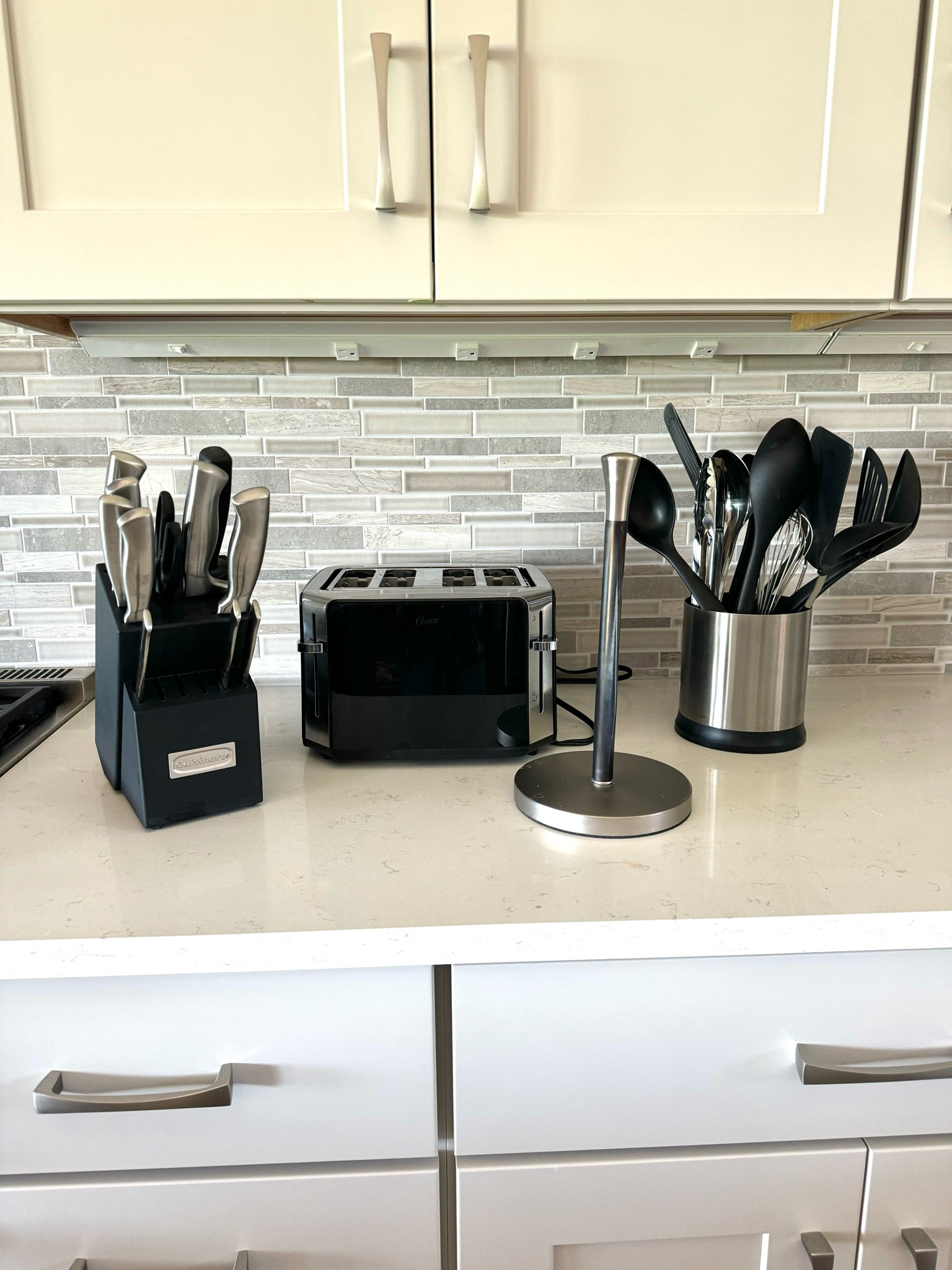 Black and stainless Modern kitchen knives, utensils and Oster toaster and paper towel holder. All look nice and on your kitchen counters 