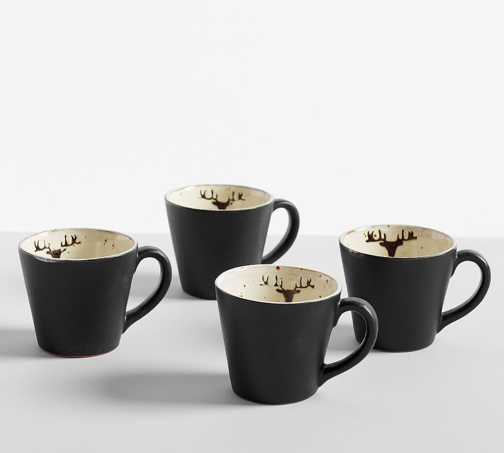 Four black stoneware mugs with a small reindeer motif