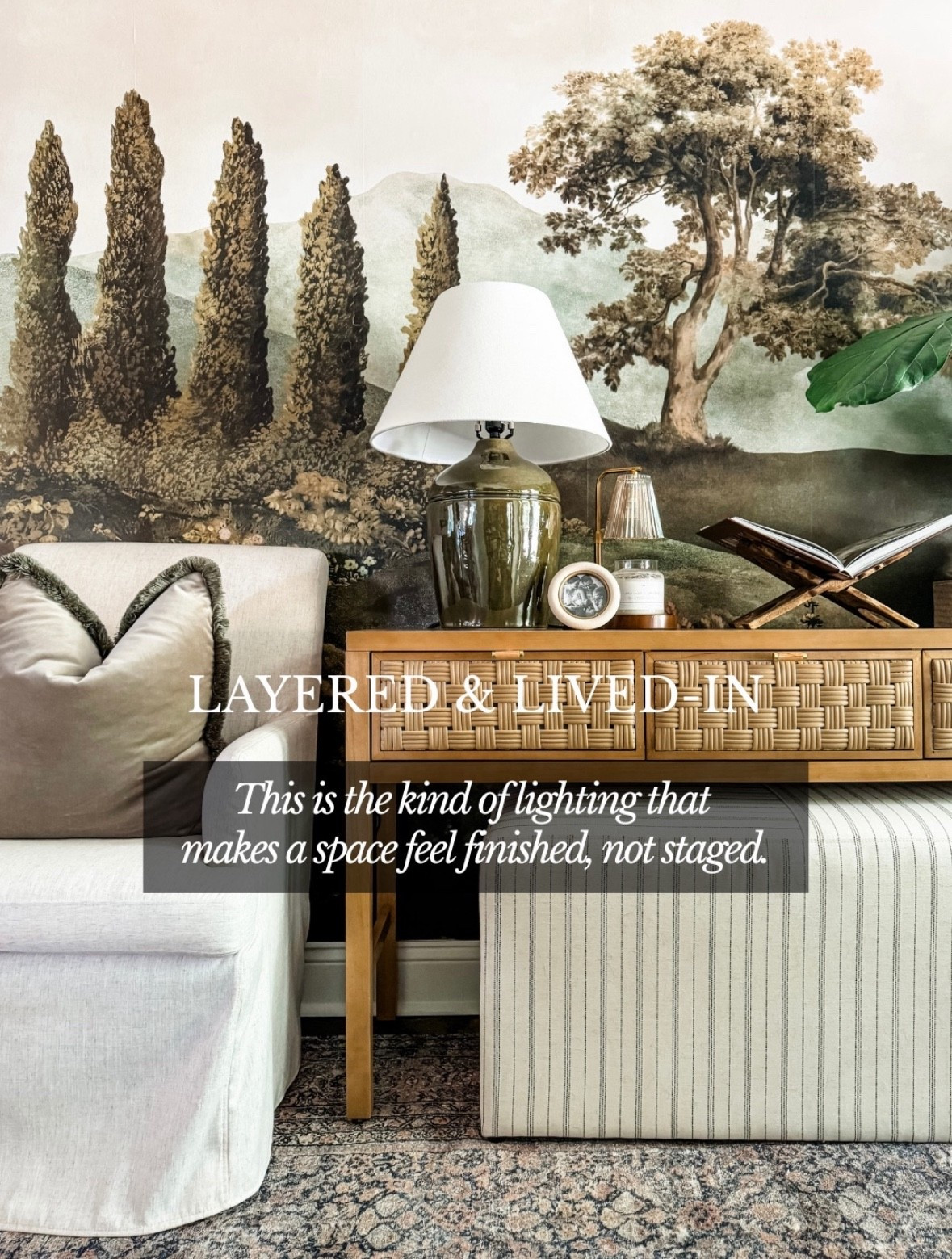 Layered, lived-in, and intentionally collected 🤍
This ceramic table lamp with a white linen lampshade adds the perfect soft glow to a woven console table, layered in front of a scenic landscape wallpaper mural. Mixed textures—rattan drawer fronts, warm wood furniture, neutral upholstered seating, striped ottoman, and a vintage-inspired area rug—create a space that feels finished, not staged. Thoughtful ambient lighting, decorative objects, and classic styling make this corner cozy, timeless, and effortlessly inviting. Everything is linked on LTK ✨

#eanesinteriors #tablelamp #ambientlighting #layeredlighting #wovenfurniture #rattanconsole #neutralinteriors #classicdecor #traditionalhome #livingroominspo #cozycorners #interiorstyling #ltkhome #ltkinspo

#LTKSeasonal #LTKHome #LTKstorytime