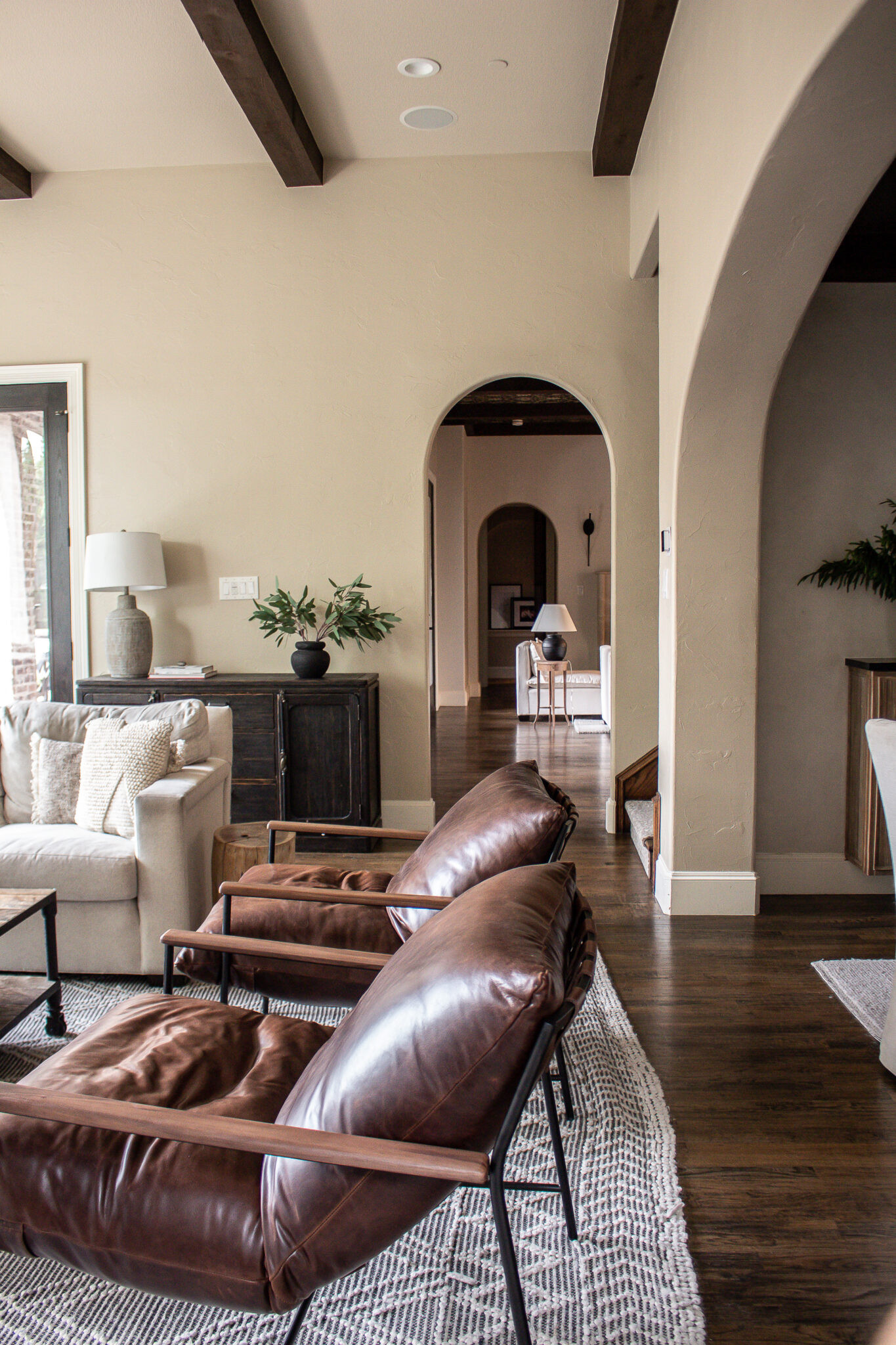 Neutral living room with warm wood tones, leather seating, arched doorways, and exposed ceiling beams. A cozy yet elevated space layered with texture, natural light, and timeless finishes.

#LTKHome #LTKmomlife #LTKSeasonal