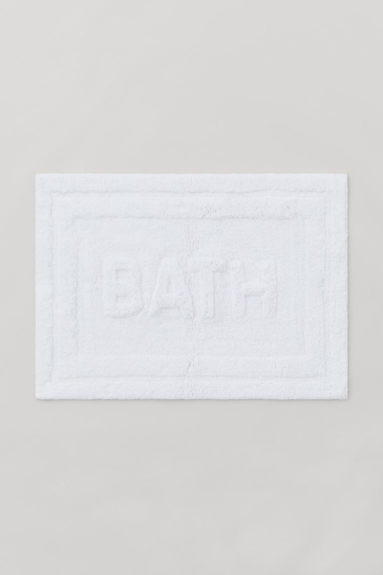 Rectangular bath mat in thick cotton terry with a tone-on-tone text motif at front. Non-slip prot... | H&M (US)