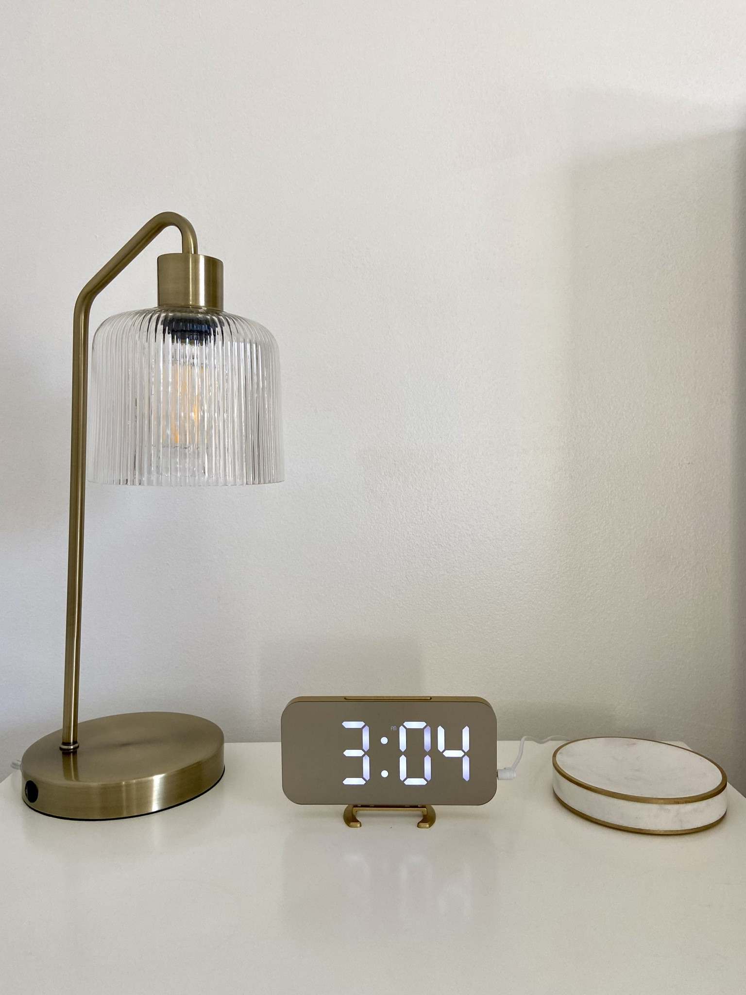 Simple yet functional Al nightstand decor. Quiet glam nightstand pieces 
Gold modern glass lamp. Gold modern digital clock. Marble tray / coaster. 

#LTKMostLoved #LTKhome #LTKfindsunder50