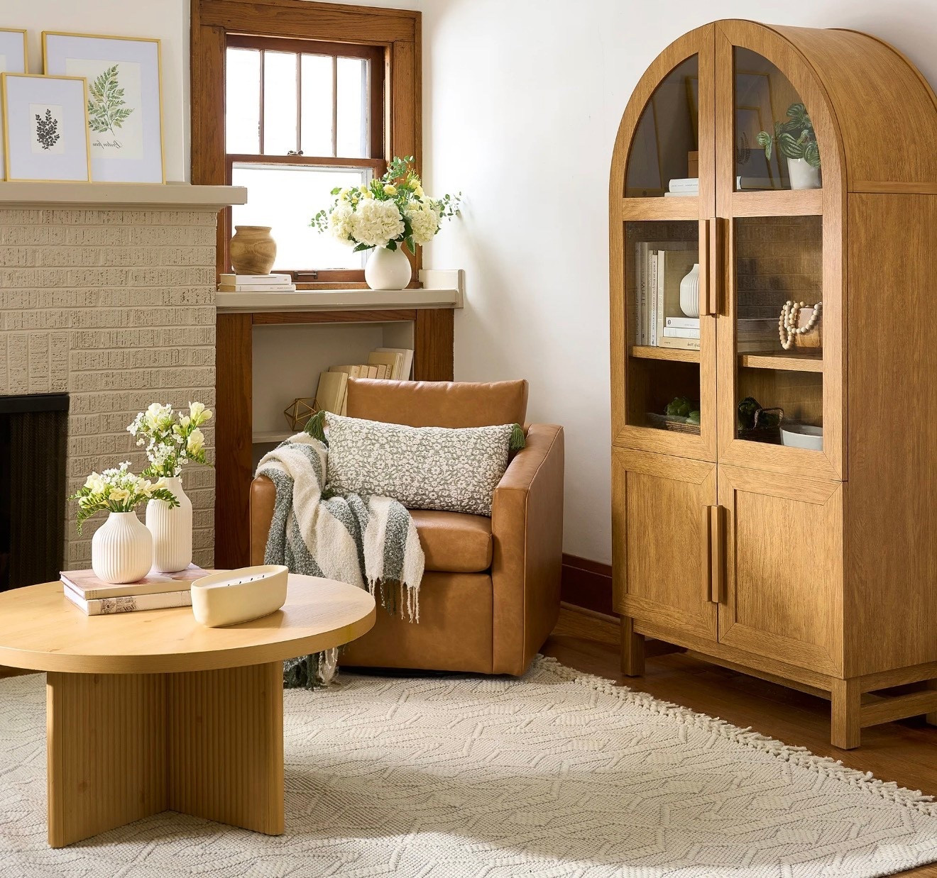 A warm, sunlit living room styled in a modern organic aesthetic. A caramel leather armchair sits beside a light oak arched glass cabinet filled with neutral books and ceramic decor. A round light-wood coffee table rests on a textured cream area rug. Soft white florals in minimalist vases, layered throw pillows, and cozy textiles create a calm, lived-in feel. Natural wood trim, neutral tones, and gentle daylight evoke quiet luxury, timeless comfort, and elevated simplicity. Ultra-realistic, editorial interior photography, soft shadows, natural textures.

⸻

Hashtags (25)

#OrganicModern
#NeutralHome
#QuietLuxuryHome
#ModernTraditional
#CozyLivingRoom
#TimelessInteriors
#WarmNeutrals
#ElevatedLiving
#HomeInspo
#InteriorAesthetic
#OrganicTextures
#ModernFarmhouse
#NeutralDecor
#SlowLiving
#ThoughtfulDesign
#ClassicHome
#InteriorStyling
#MinimalWarmth
#NaturalMaterials
#LivingRoomGoals
#DesignDetails
#SoftNeutrals
#HomeEdit
#EffortlessStyle
#CalmSpaces

#LTKHoliday #LTKGiftGuide #LTKdayinmylife