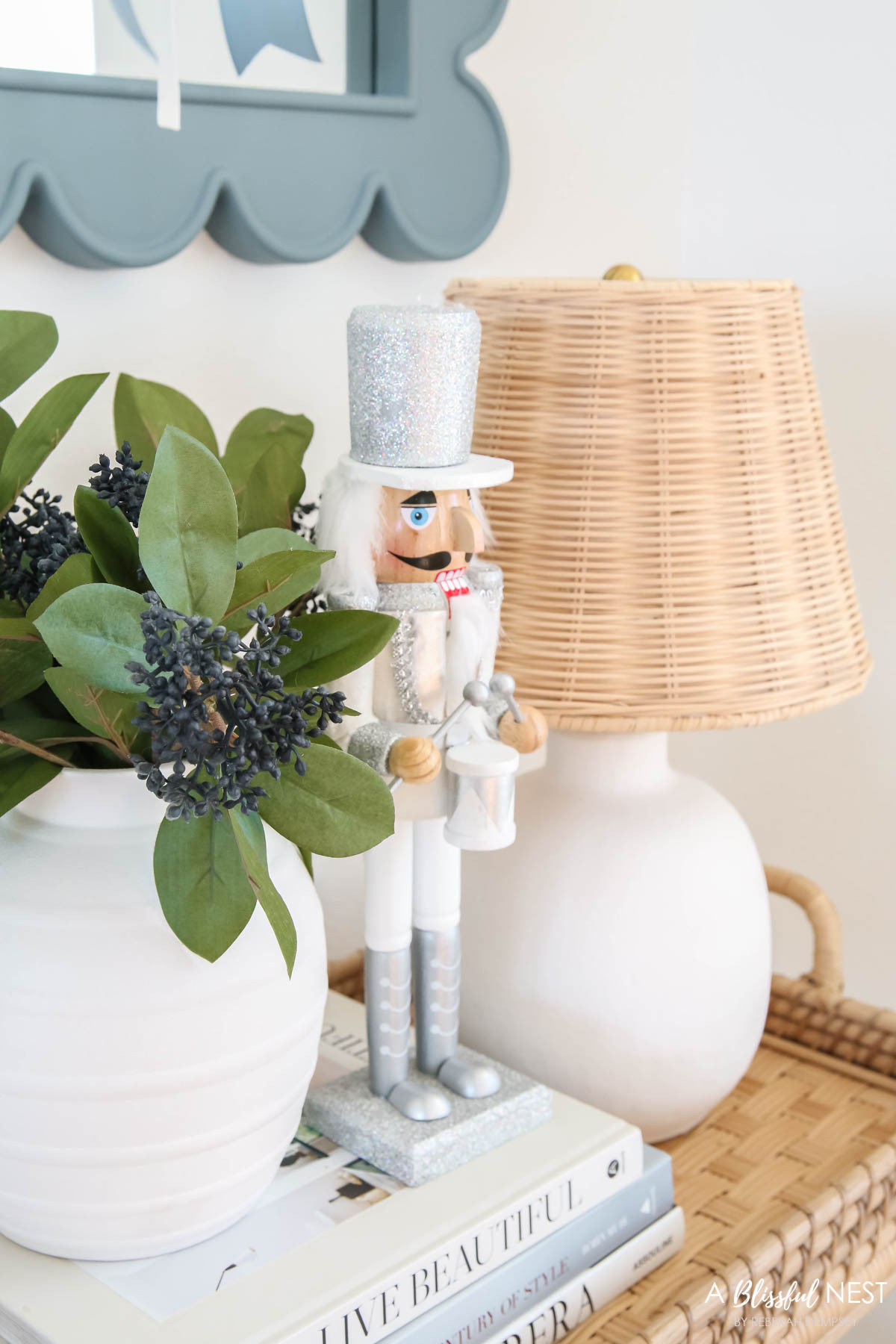 A calm and cozy Christmas corner that still feels festive and welcoming. Snag the decor here.
rattan bar cart, rattan shade table lamp, blue berry greenery picks, ivory velvet ribbon, dusty blue ribbon, scallop mirror, textured ribbed vase, silver Christmas soldier 

 #LTKHoliday #LTKSeasonal #LTKHome