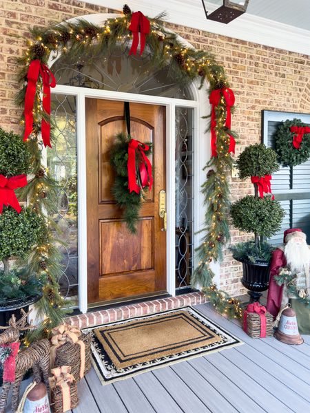 Classic Christmas front porch decorated with reds. Large Santa and grapevine presents and deer complete the space! 

Front door | outdoor Christmas decor | topiaries 

#LTKHoliday #LTKSeasonal #LTKhome