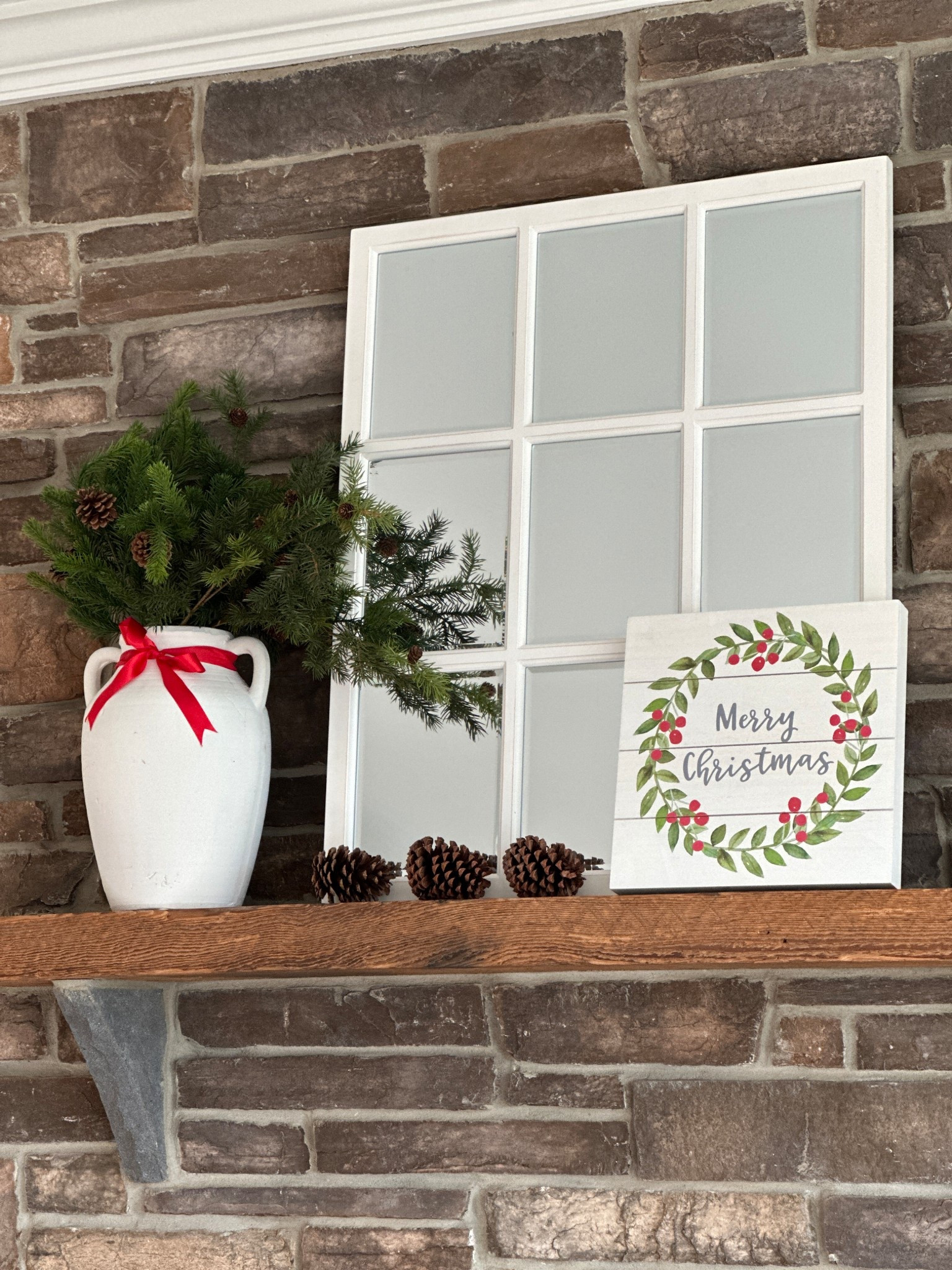 Simple mantel decor for Christmas.  Window pane mirror, white vase filled with greenery and pine cones.

#LTKHome #LTKHoliday #LTKSeasonal