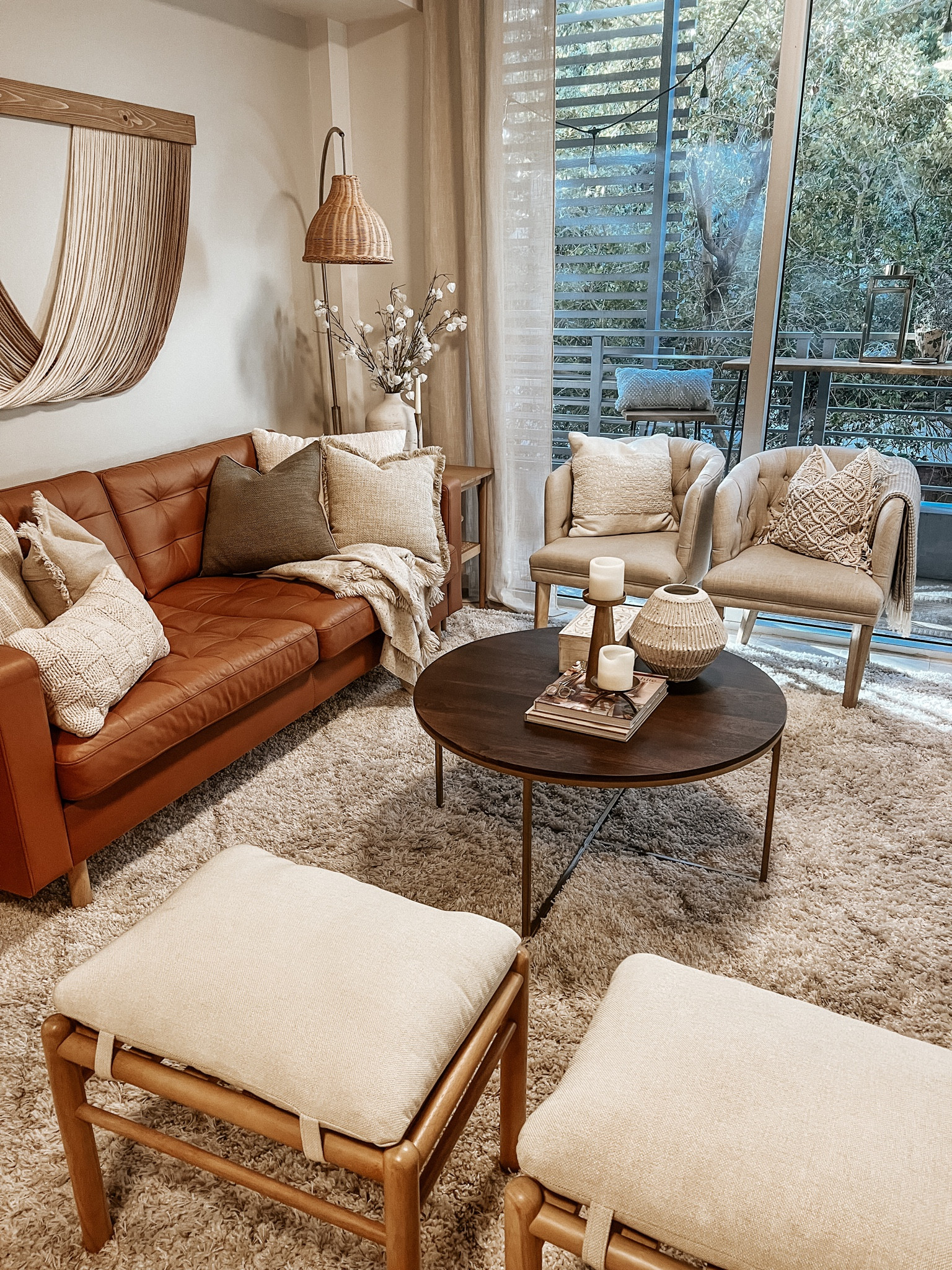 neutral boho living room 

Leather couch, cozy rug, ottomans, accent chair, coffee table, throw pillows, fiber art, rattan lamp, ceramic vase, gold candle holders 

#LTKunder50 #LTKhome