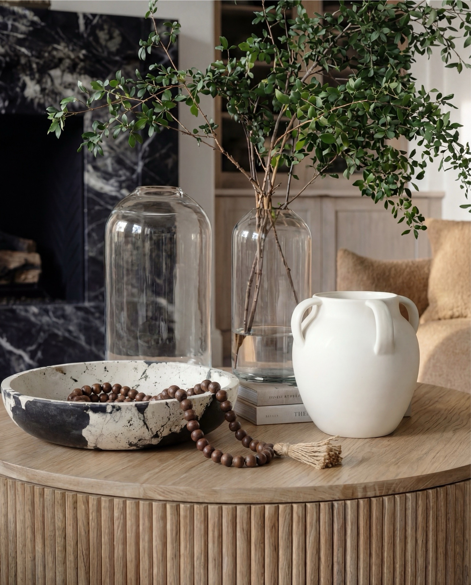 Shop the Look:
• Brown upholstered sofa (textured fabric)
• Brown upholstered accent chair
• Round fluted wood coffee table
• Black ribbed side table
• Neutral vintage-style area rug (cream + taupe)
• White boucle pouf ottomans
• Chunky knit throw blanket (warm neutral)
• White globe pendant light
• Exposed wood ceiling beams
• Arched doorway detail
• Black-framed arched windows
• Dark marble fireplace surround
• Wood built-in cabinet with glass doors
• Ceramic vases (white + stone tones)
• Decorative pottery vessels
• Coffee table books (neutral covers)
• Indoor greenery in glass vase
• Framed abstract artwork (earth tones)

#LTKSaleAlert #LTKHome