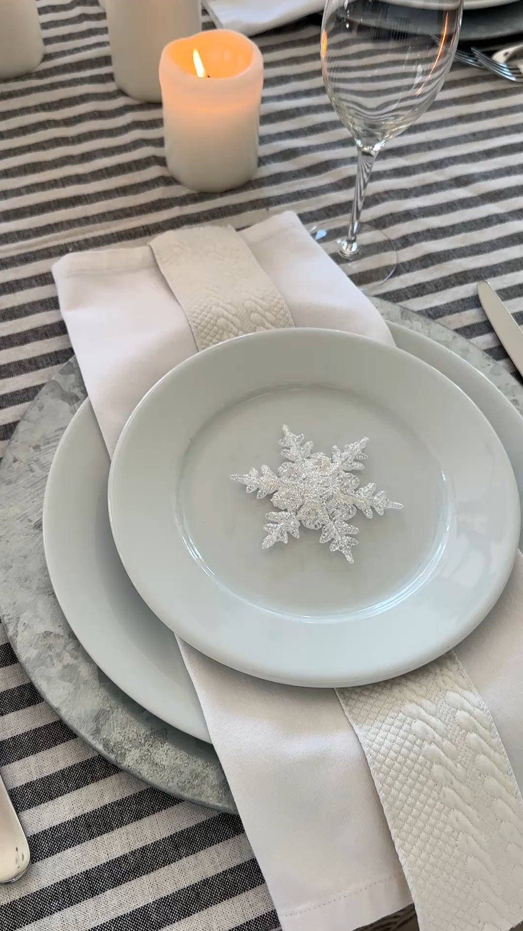 Winter white table setting with snowflakes, white candles, white dishes and a gray and white striped tablecloth.

#LTKHome #LTKSeasonal #LTKFindsUnder100