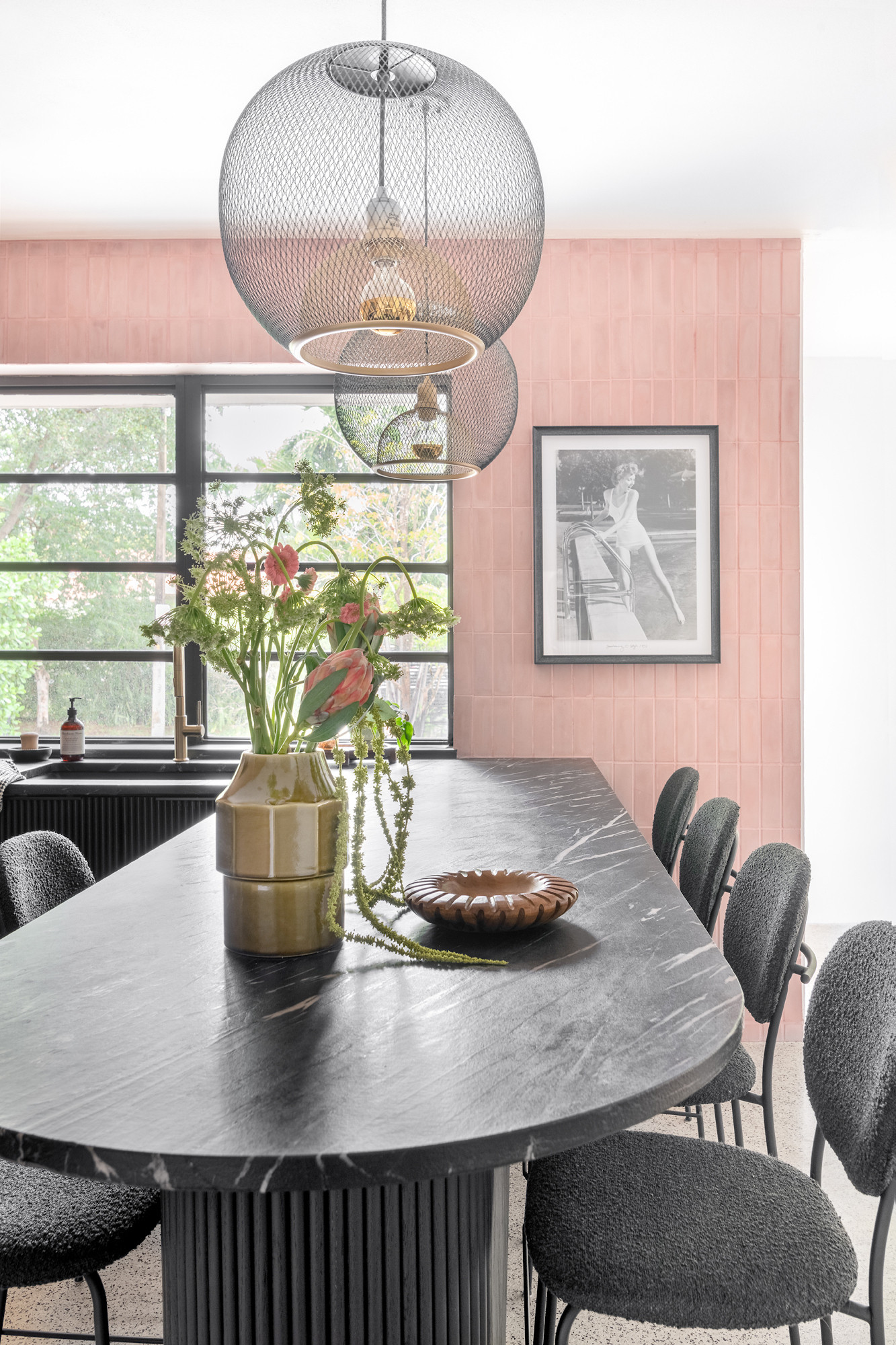 This pink, mid-century modern-inspired kitchen combines bold design choices, functional elegance, and a playful atmosphere that invites creativity. Inspired to flow with the rest of the house, we balanced contrasting materials soft pink tiles, black fluted cabinetry, and light wood upper cabinets to create a harmonious yet striking space. 

 #LTKHome