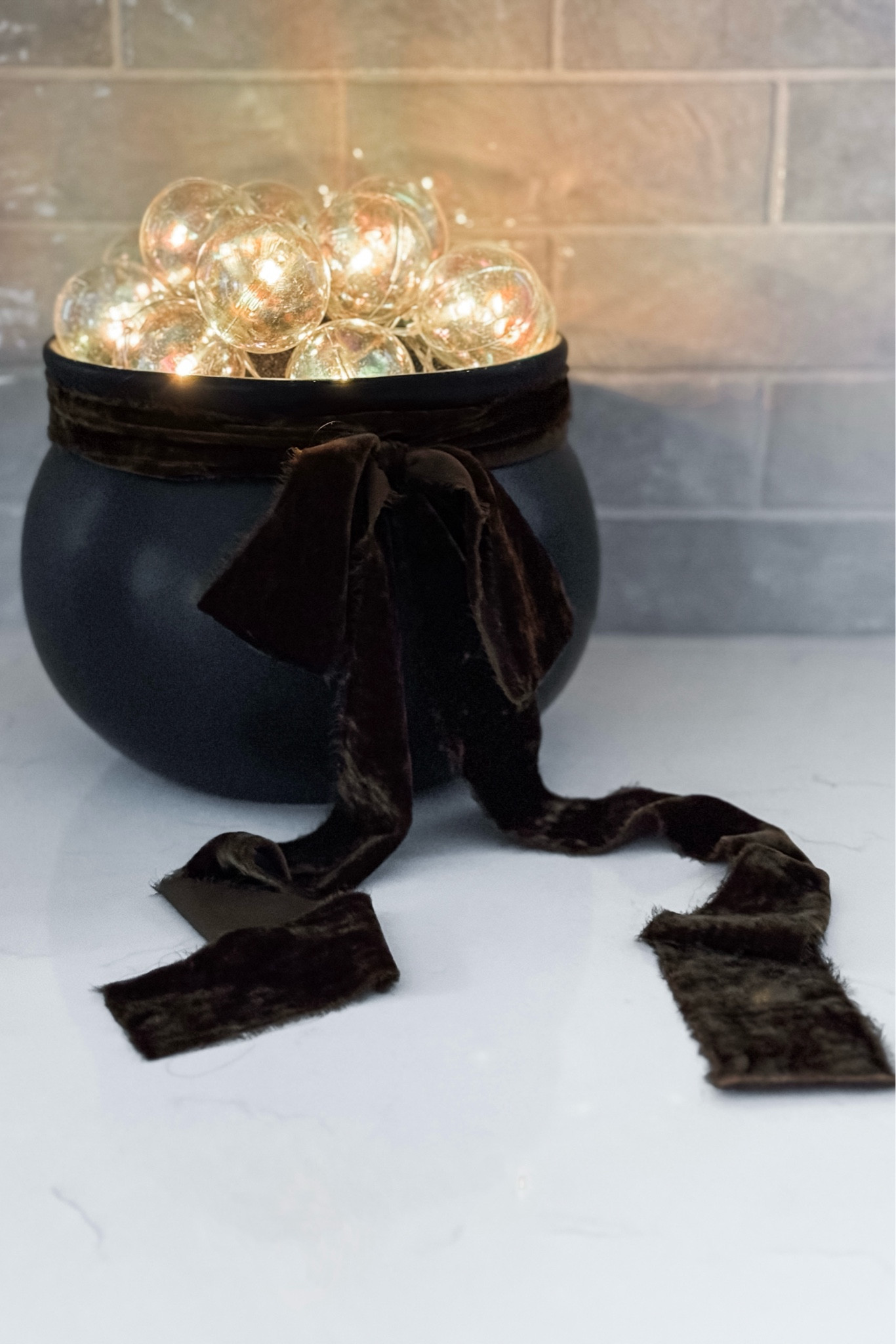 I bought this “LED Black Cauldron with Bubbles” at Kirkland’s Home for Halloween and I absolutely love how it turned out! Everything you need to achieve this look is included (there are so many parts to source / manage if you choose to DIY!), the “bubbles” are simple and easy to arrange, and it’s just the right size. 
The only part I wasn’t crazy about was the cotton ribbon that comes with the cauldron — I replaced it with my own 2” brown velvet ribbon (and still need to trim the ends a bit) which I think fits the aesthetic of our home a bit better.

I can’t link to this item directly so I’ve shared some similar options below — 

#LTKHalloween #LTKHome #LTKSeasonal