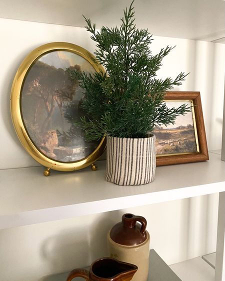 Simple holiday home decor additions 🌲. Linked the digital prints I got from Etsy- the easiest home upgrade! The brass/gold oval frame is vintage- linked some similar options

Christmas tree. Christmas decor. Shelf styling. Holiday shelf styling. Traditional home decor. Moody home decor