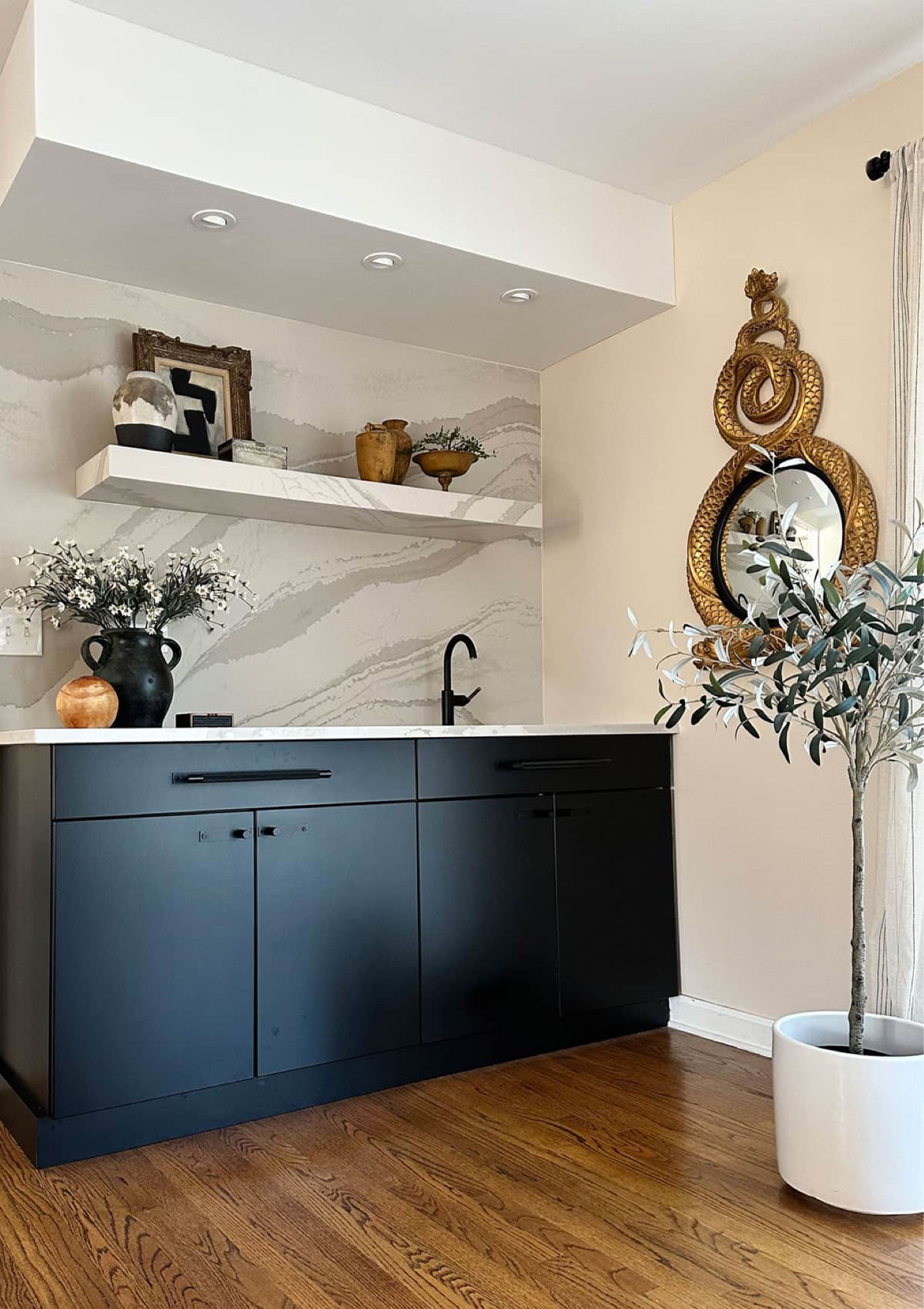 The wet bar with floating shelf was a labor of love and made of quartz from Cambria. I have a closer look at how it was made on HOH, but for today, this is how I styled it. Modern, simple, organic, and always eclectic full of vintage decor - which is always difficult to properly source. I did my best. Faux olive tree in vintage Gainey planter, original black and white abstract in antique gold frame, the snake mirror (always a hit), Brizo faucet in black matte, and simple vases. 

#LTKhome #LTKover40