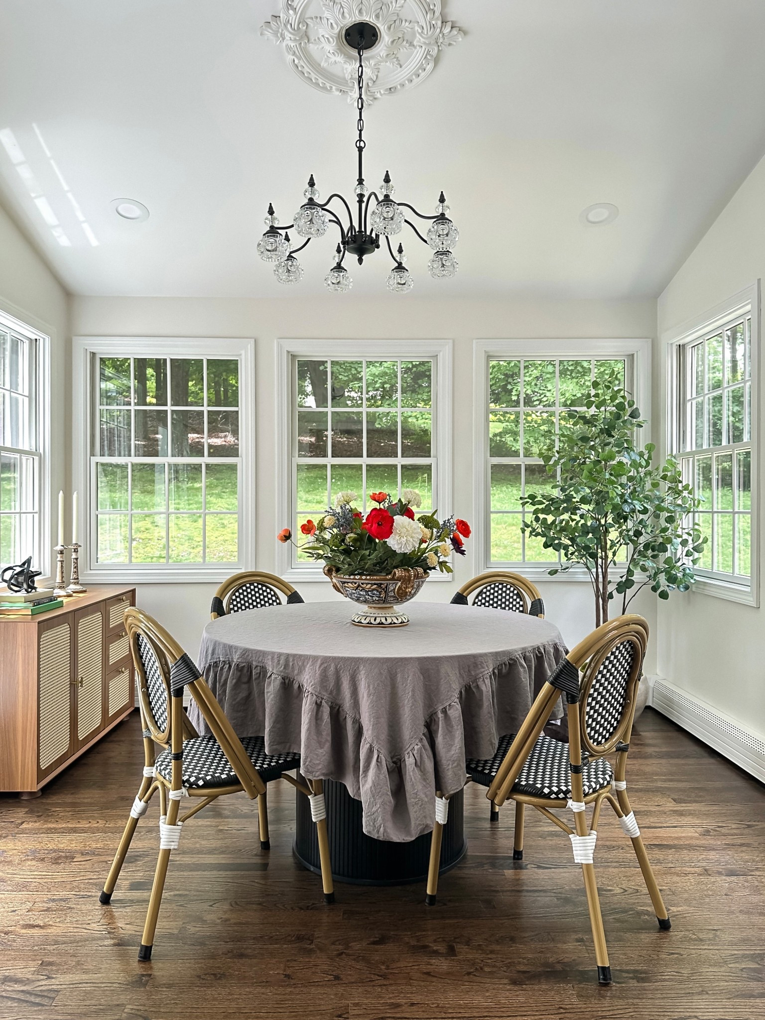Dining sunroom — French bistro / boho chic aesthetic. Ruffle tablecloth, black round dining table, bistro chairs, sideboard and vintage chandelier.

#LTKHome #LTKSeasonal #LTKFindsUnder100