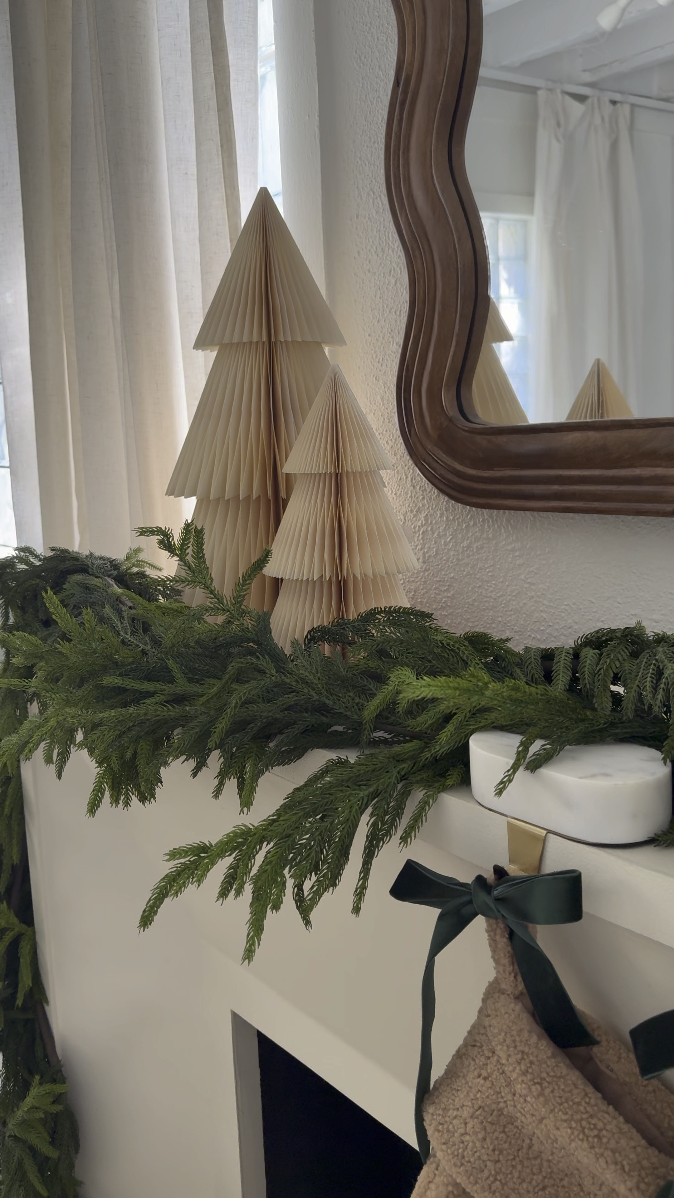 Christmas decor: how to style your fireplace mantel. Faux garland, marble stocking holders, paper Christmas trees, wooden scalloped mirror 

#LTKHome #LTKVideo #LTKHoliday