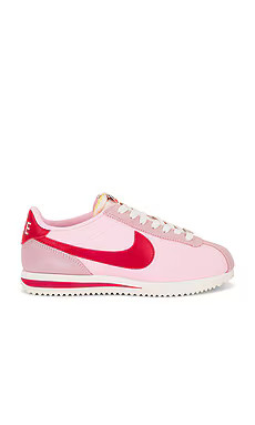 Nike Cortez Textile Sneaker in Medium Soft Pink, Fire Red, Sail, & Team Orange from Revolve.com | Revolve Clothing (Global)