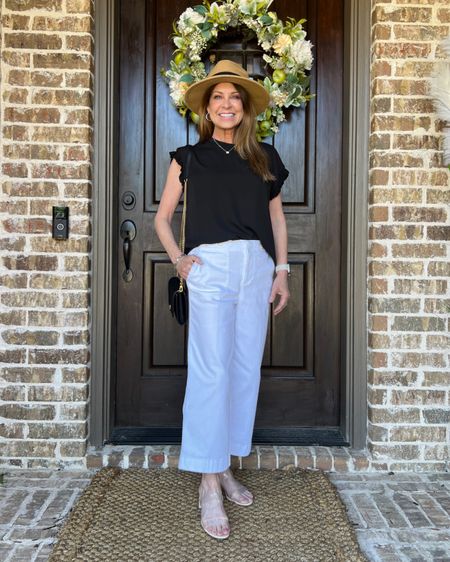 A classic black and white outfit for spring and summer. I'm wearing a black top with ruffle sleeves and white cropped jeans. It's so versatile. My top is size small, and my jeans are size 2P, but I wish they were a bit longer. I would have preferred regular size 2 if they were available. I'm also wearing low heels with clear straps that match everything. My hat has UPF protection, and a crossbody bag is always a good choice.
#classicstyle #midlifefashion #outfitidea #vacationlook 

#LTKSeasonal #LTKShoeCrush #LTKStyleTip