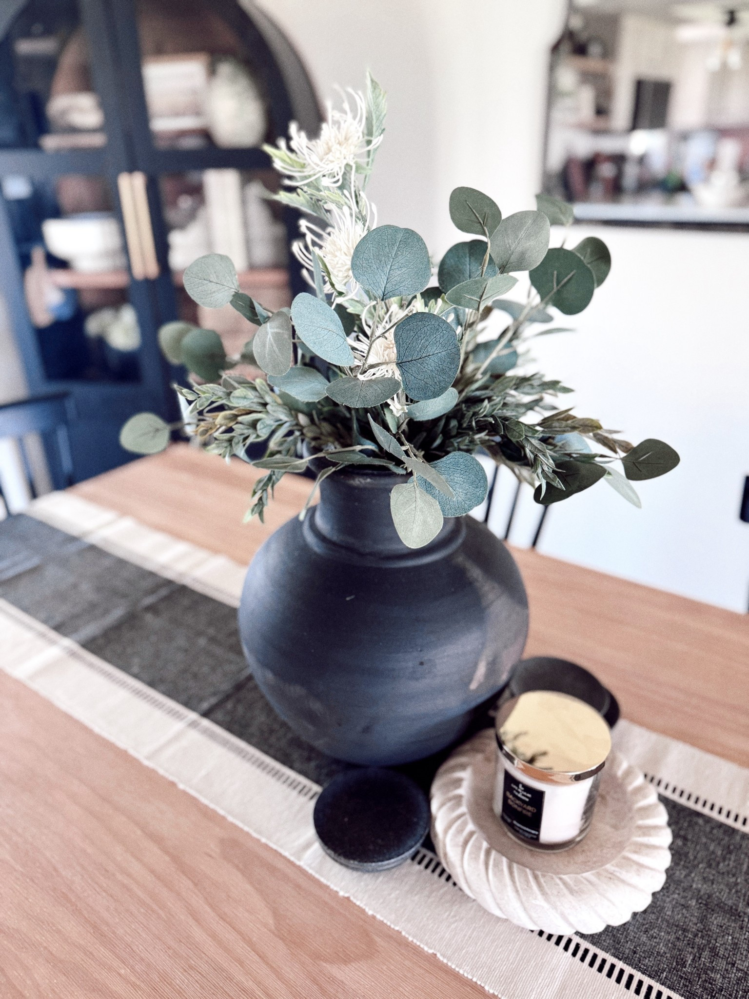 Neutral home details I’m loving lately 🤍

This matte black vase, faux eucalyptus stems, and candle moment make the perfect dining table centerpiece. Everything is styled on a striped table runner for a cozy, layered look.

#LTKhome #LTKdecor #neutralhome #tablescape #LTKfinds #diningtabledecor #vasedecor #modernneutral #homedetails
