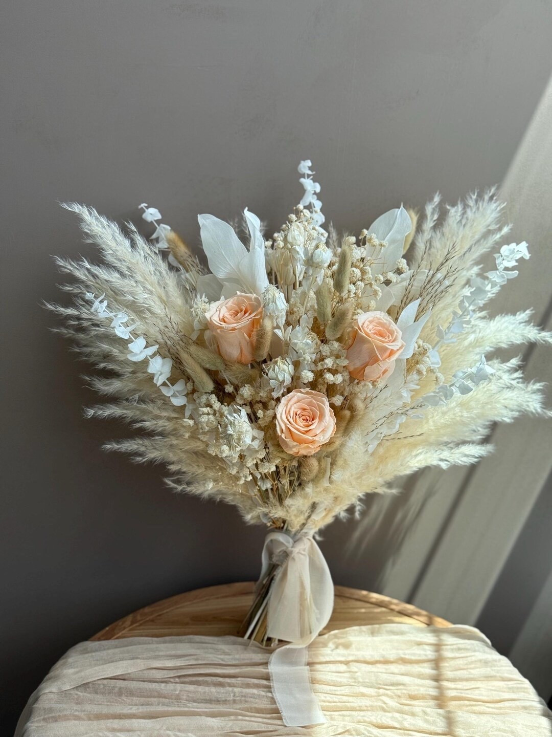 Soft peach tones and airy textures make this handcrafted dried bouquet by EverdriedBloom a timeless addition to any home. Featuring preserved eucalyptus, delicate baby’s breath, roses, pampas grass, ruscus, and fluffy bunny tails, this arrangement blends warm neutrals with romantic softness. Made from real preserved botanicals, it offers lasting beauty with zero maintenance. Style it as a cozy centerpiece, shelf accent, or thoughtful gift—available with or without a vase for an effortless decorating moment.

#LTKhome #driedflowerdecor #pampasgrass #neutraldecor #bohodecor #romantichome #homedecorinspo #everlastingflowers #ltkstyle #naturaldecor

#LTKHome #LTKSeasonal #LTKSpringSale