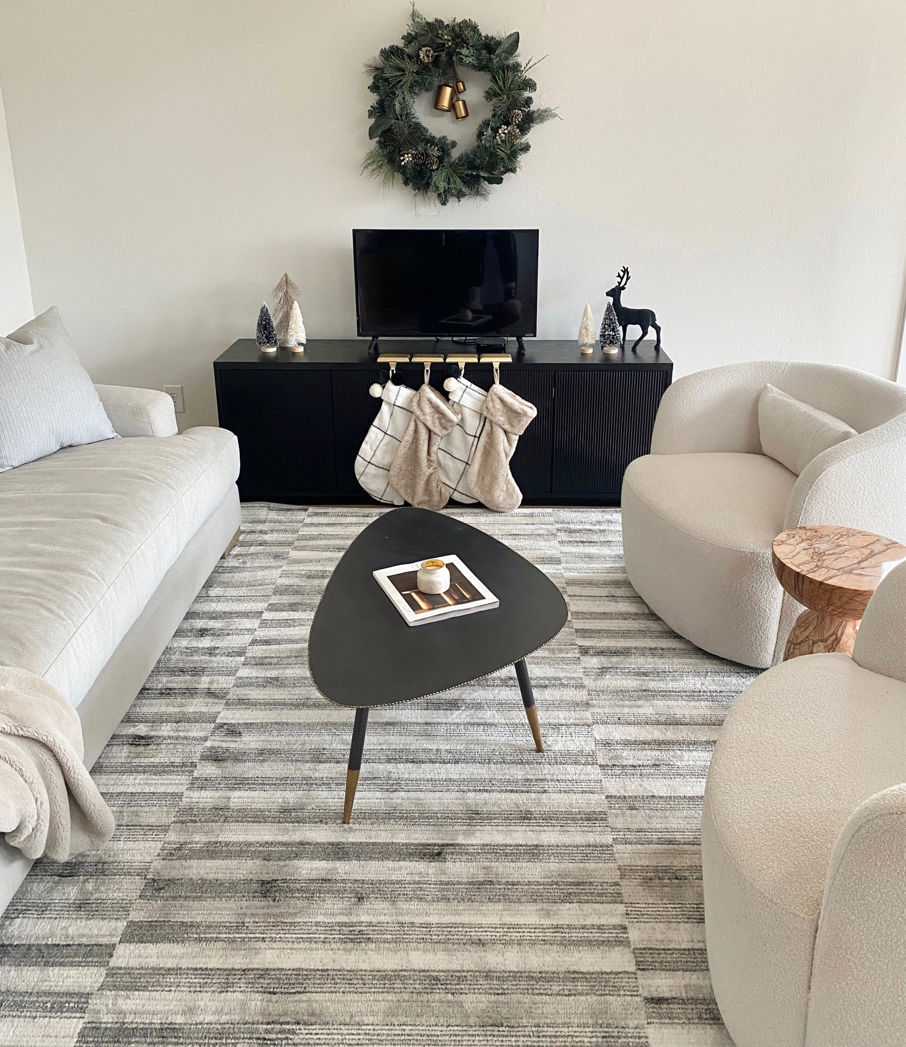 Bright and cozy neutral living room. The perfect sofa, boucle swivel accent chairs, minimal modern area rug, edgy marble end table and black coffee table and media console. 

#LTKHome