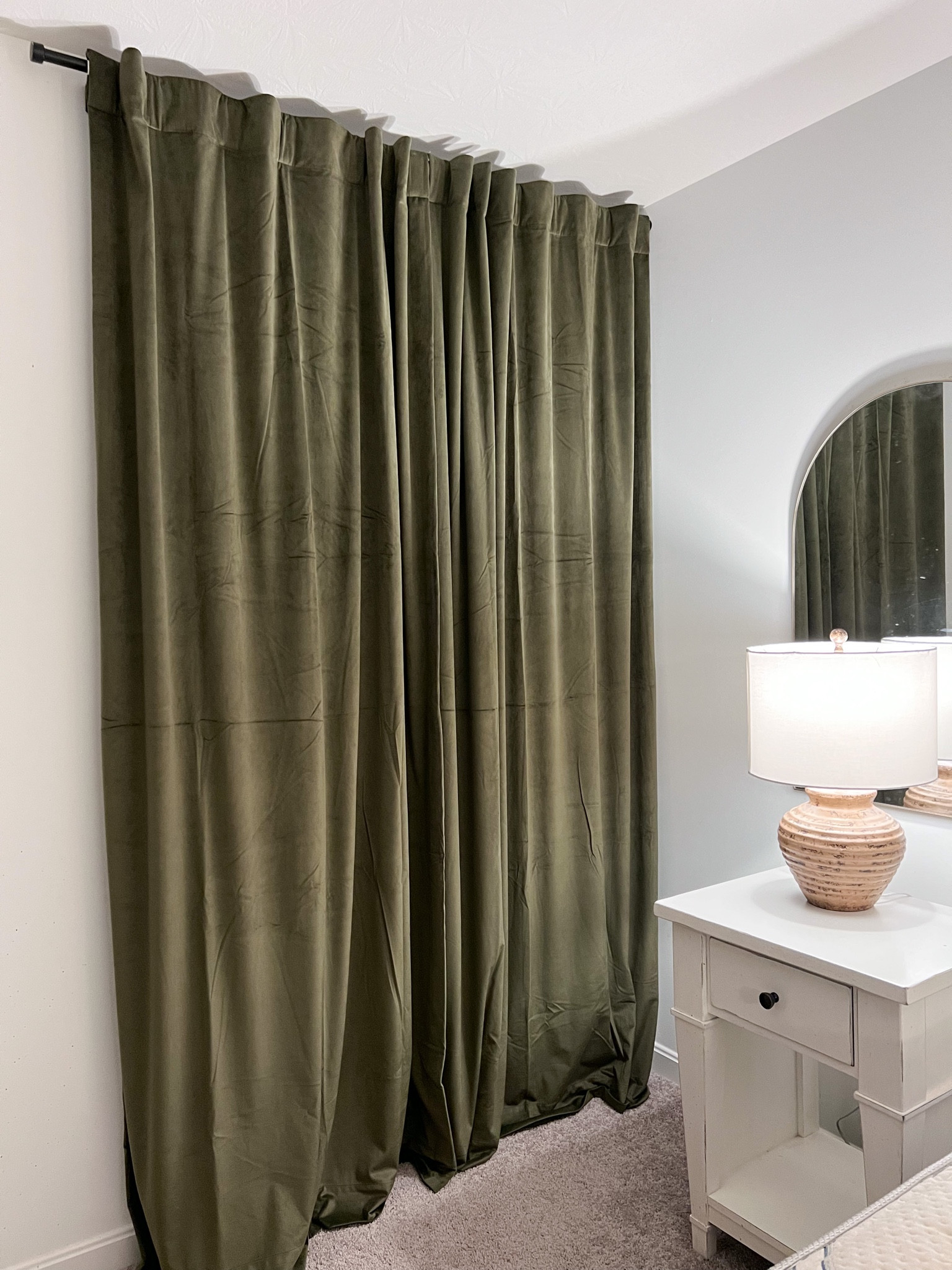 A view of the curtains at night and closed 🤩 just sooo rich and cozy! 

Velvet green curtains, table lamp, arch mirror 